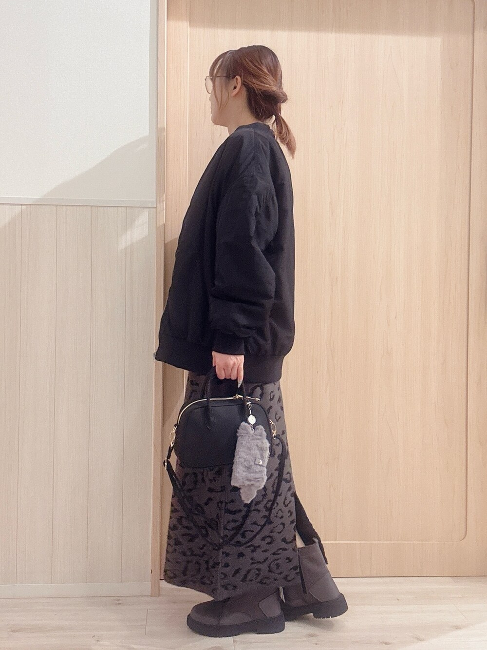 ブラウン系のブーツ、ブラック系のボストンバッグ、グレー系のスカートを着用したレディースの冬コーディネートの2枚目の写真