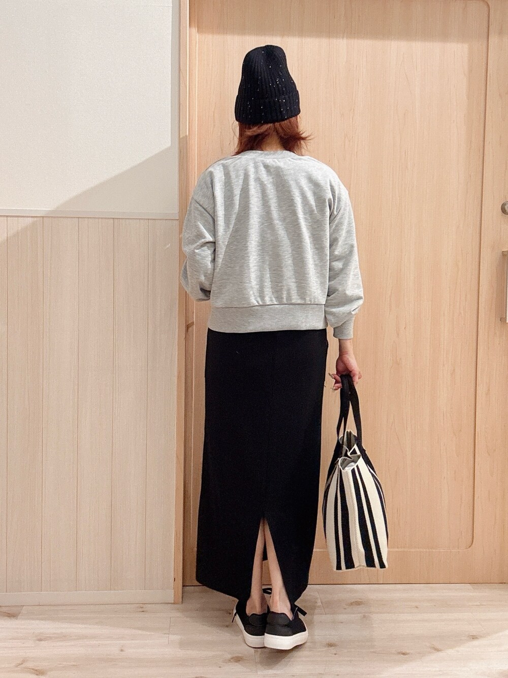 ブラック系のスニーカー、ブラック系のスカート、ブラウン系のトートバッグを着用したレディースの秋コーディネートの3枚目の写真