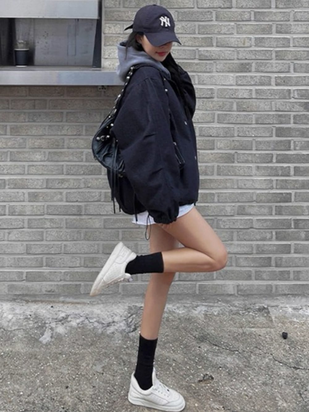 ブルー系のデニムジャケット、ホワイト系のスニーカー、ブルー系のキャップを着用したレディースの秋コーディネートの2枚目の写真