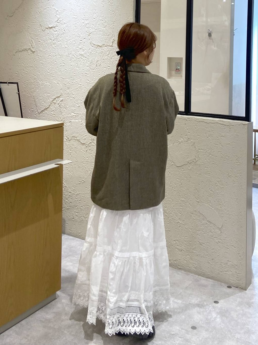 ブラウン系のテーラードジャケット、ブラウン系のサンダル、ホワイト系のスカートを着用したレディースの冬コーディネートの3枚目の写真