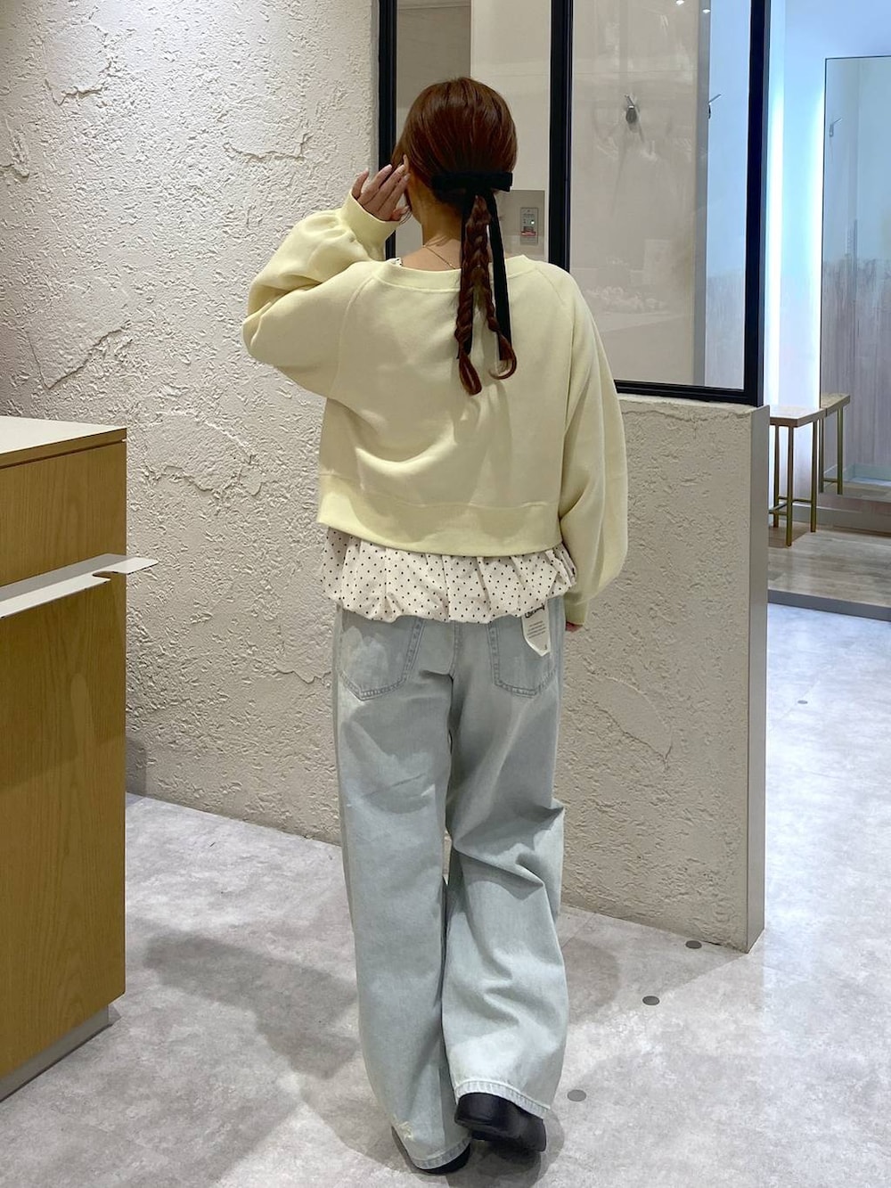 ブルー系のデニムパンツ、ブラウン系のサンダル、イエロー系のスウェットを着用したレディースの冬コーディネートの3枚目の写真