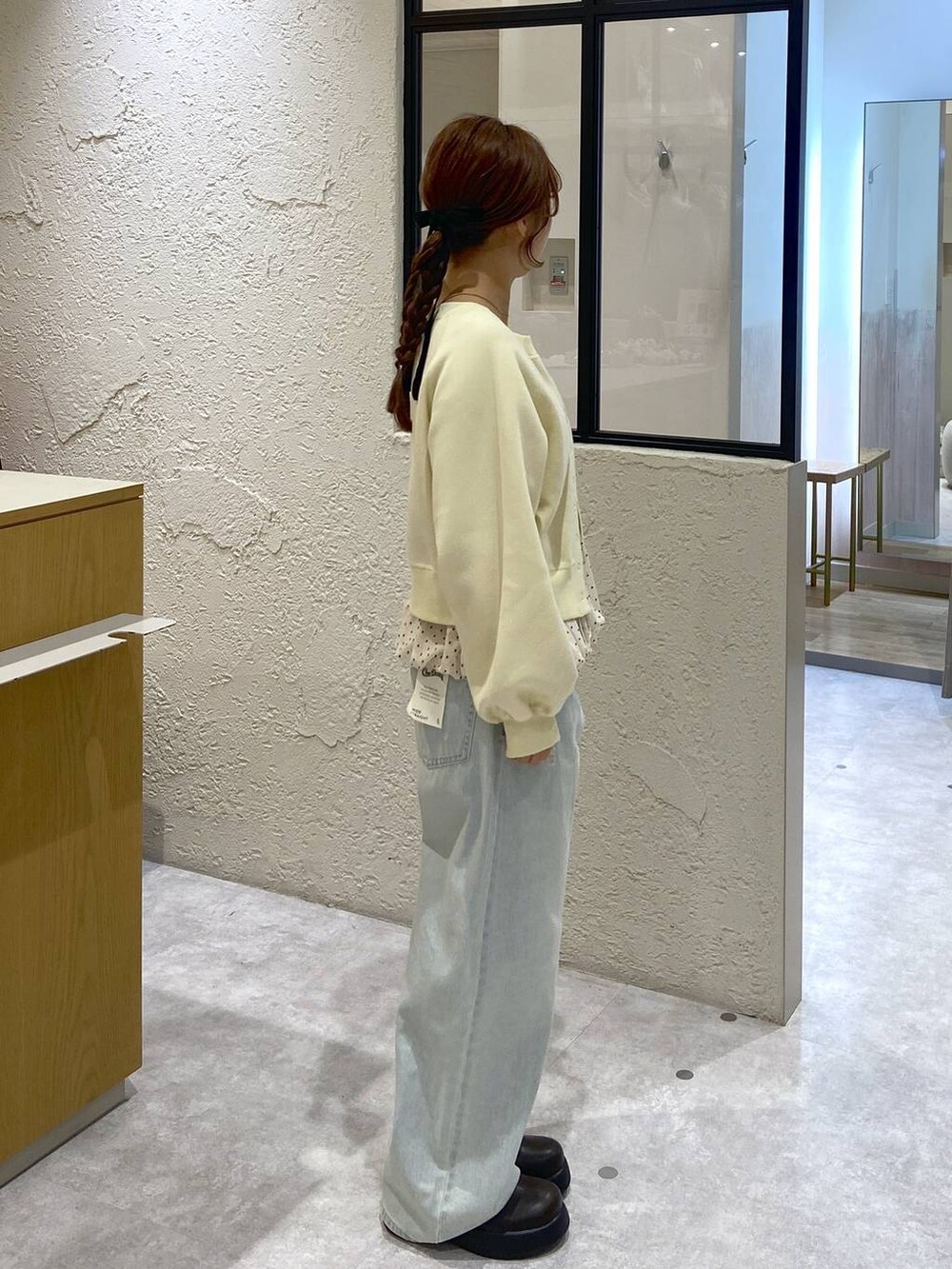 ブルー系のデニムパンツ、ブラウン系のサンダル、イエロー系のスウェットを着用したレディースの冬コーディネートの4枚目の写真