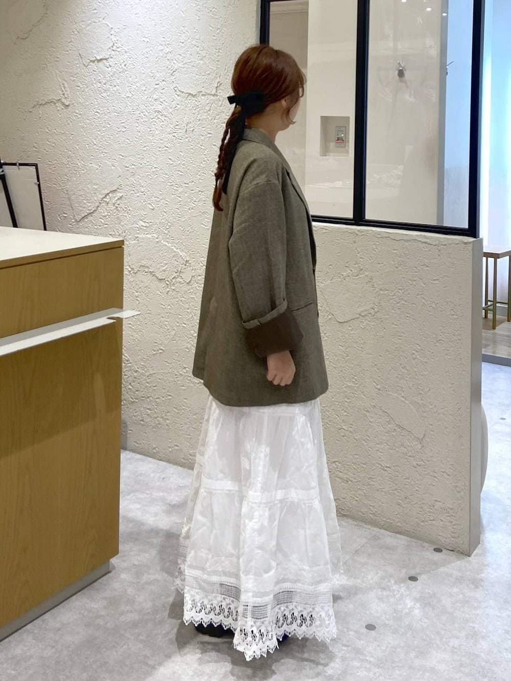 ブラウン系のテーラードジャケット、ブラウン系のサンダル、ホワイト系のスカートを着用したレディースの冬コーディネートの4枚目の写真