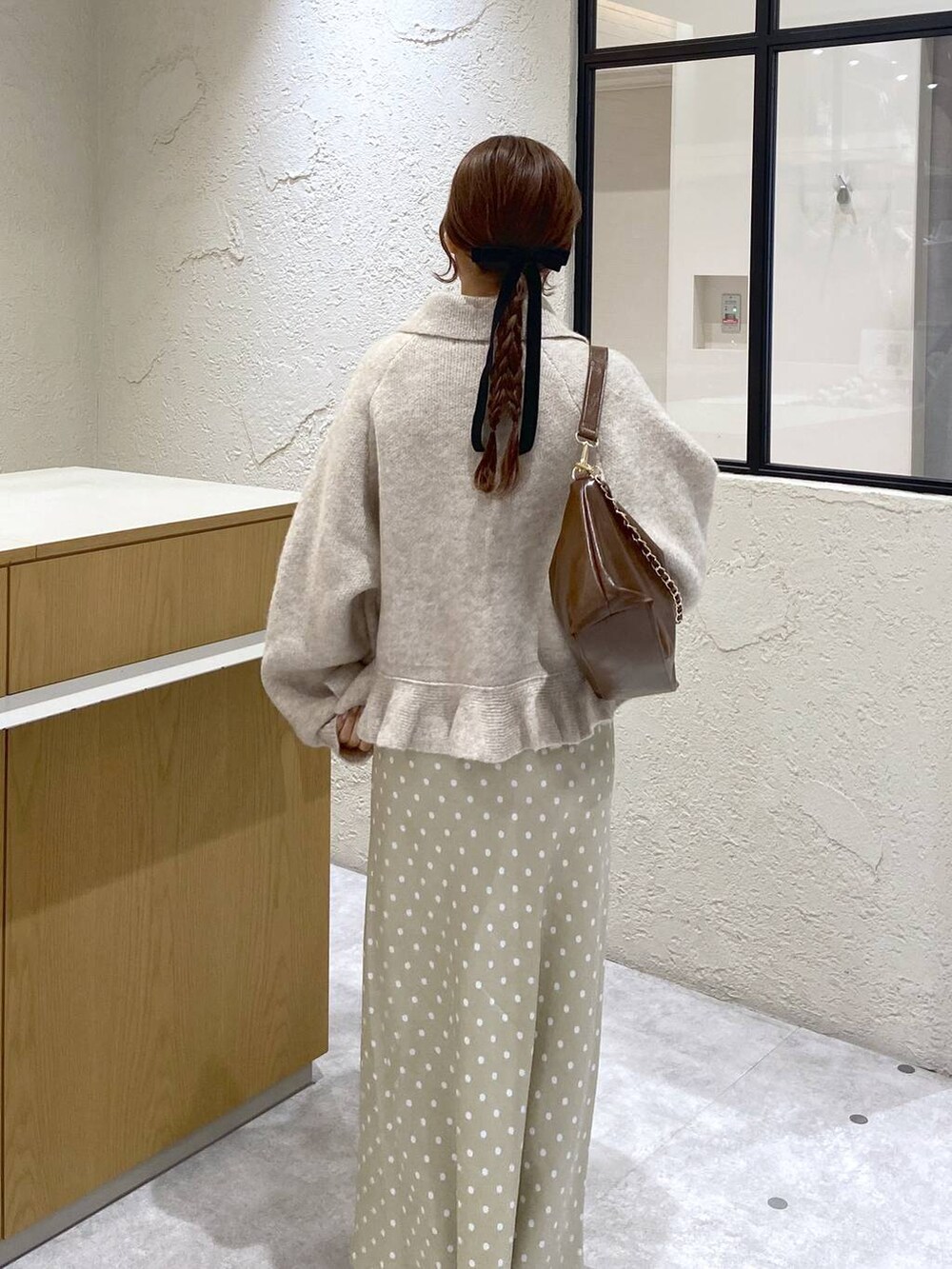 ベージュ系のスカート、ブラウン系のショルダーバッグ、ホワイト系のブルゾンを着用したレディースの冬コーディネートの4枚目の写真