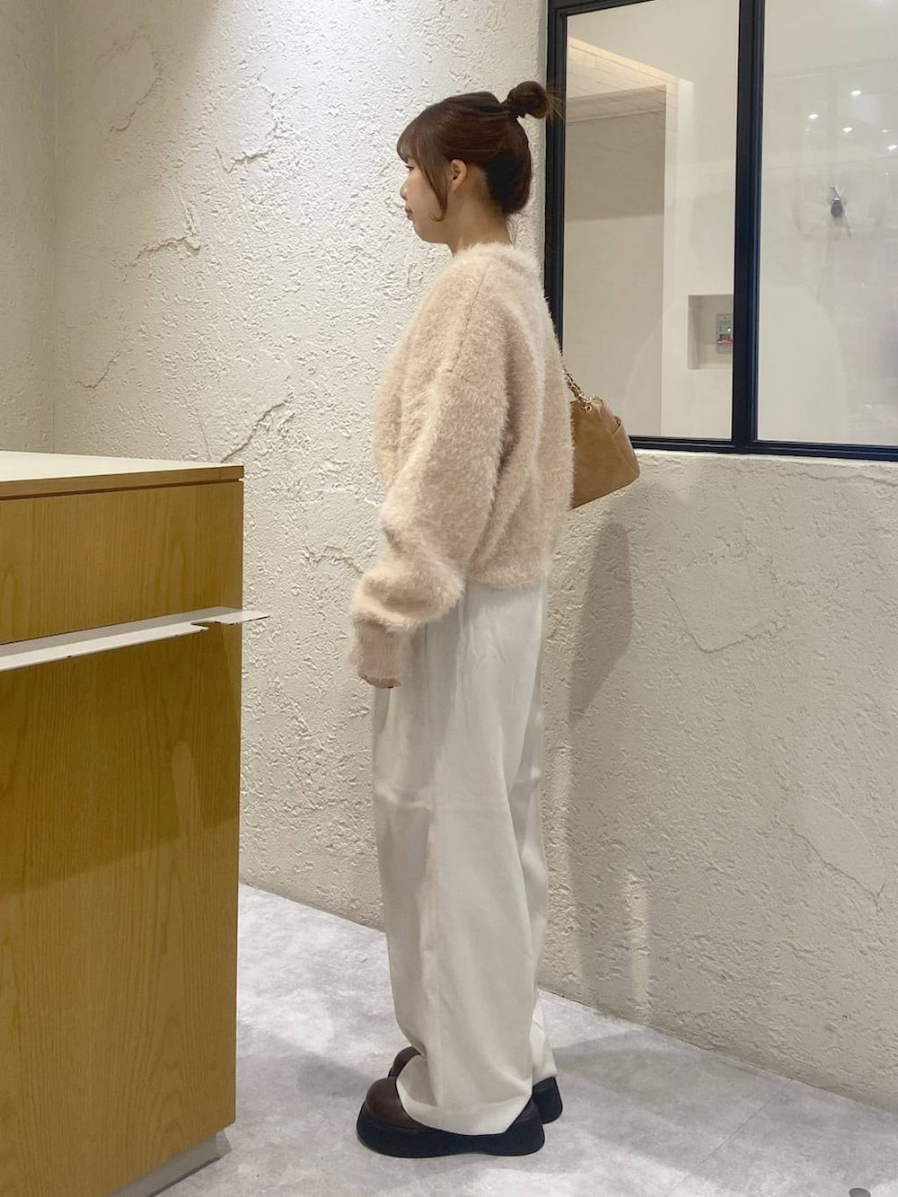 ホワイト系のスラックス、ブラウン系のサンダル、ホワイト系のニット/セーターを着用したレディースの秋コーディネートの2枚目の写真