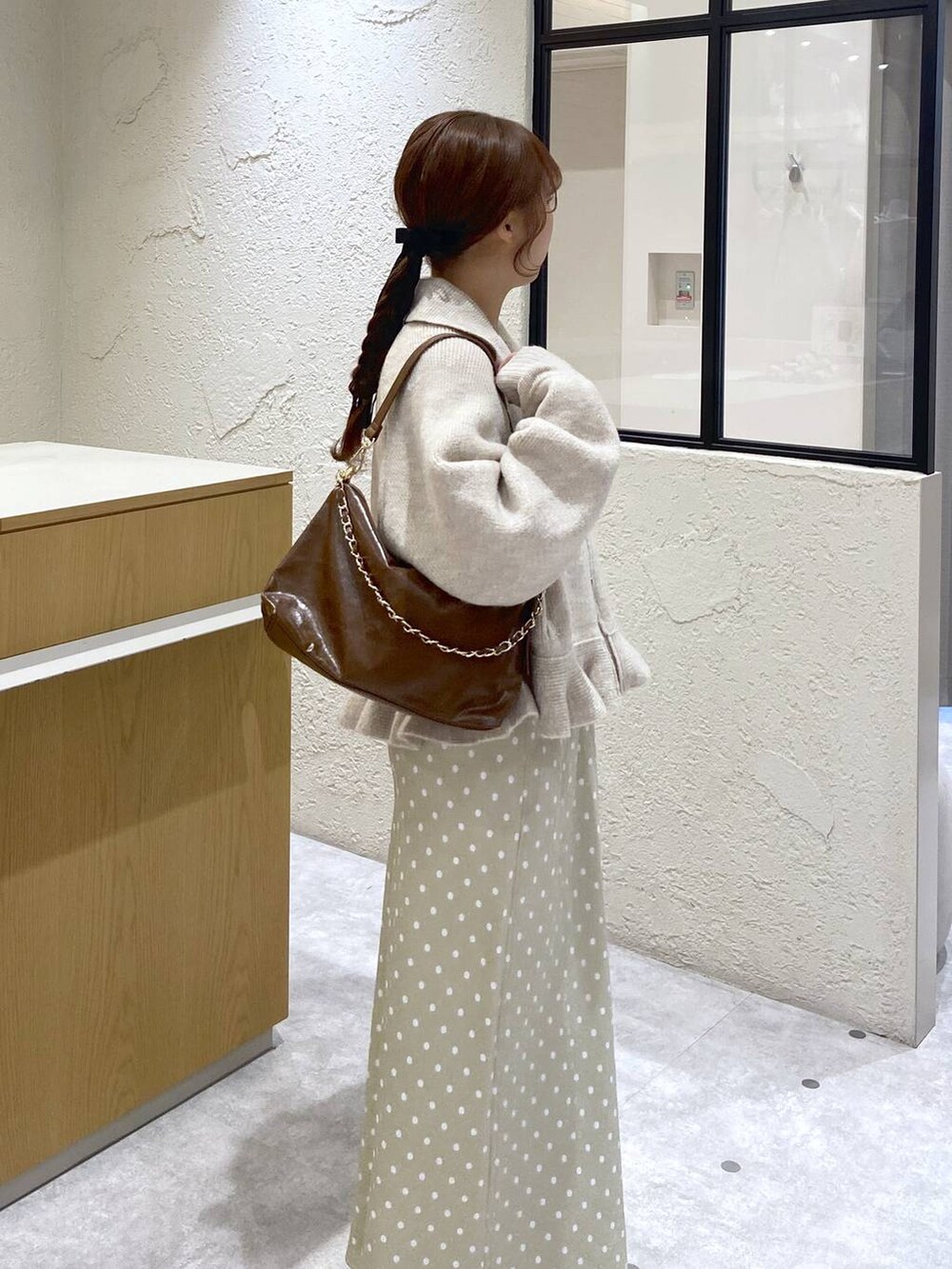 ベージュ系のスカート、ブラウン系のショルダーバッグ、ホワイト系のブルゾンを着用したレディースの冬コーディネートの3枚目の写真