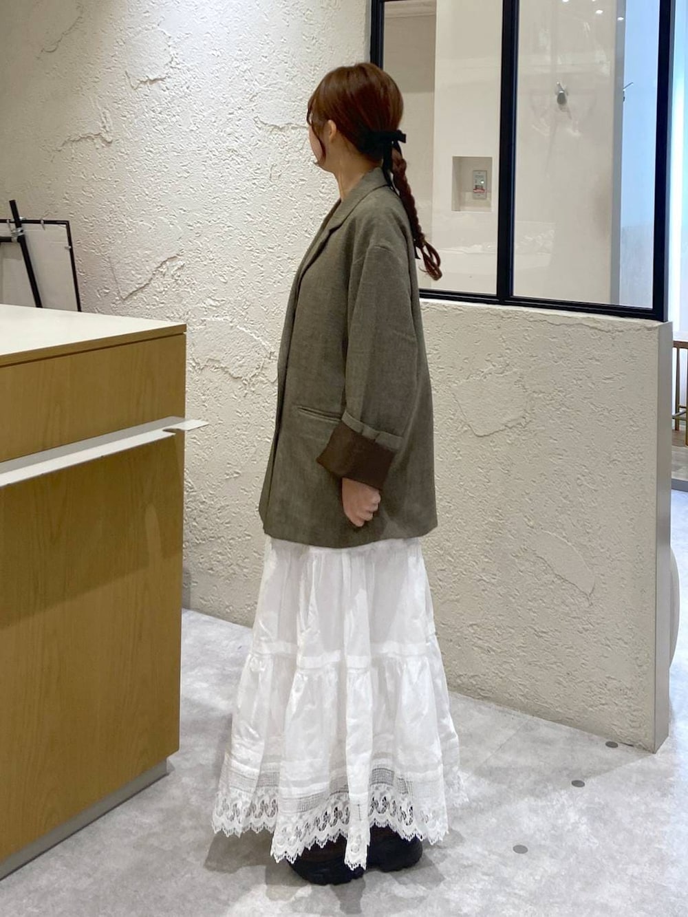 ブラウン系のテーラードジャケット、ブラウン系のサンダル、ホワイト系のスカートを着用したレディースの冬コーディネートの2枚目の写真