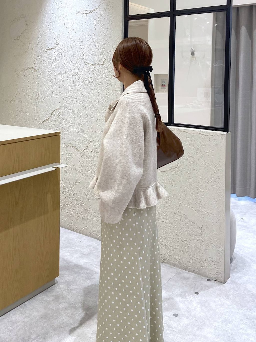 ベージュ系のスカート、ブラウン系のショルダーバッグ、ホワイト系のブルゾンを着用したレディースの冬コーディネートの2枚目の写真