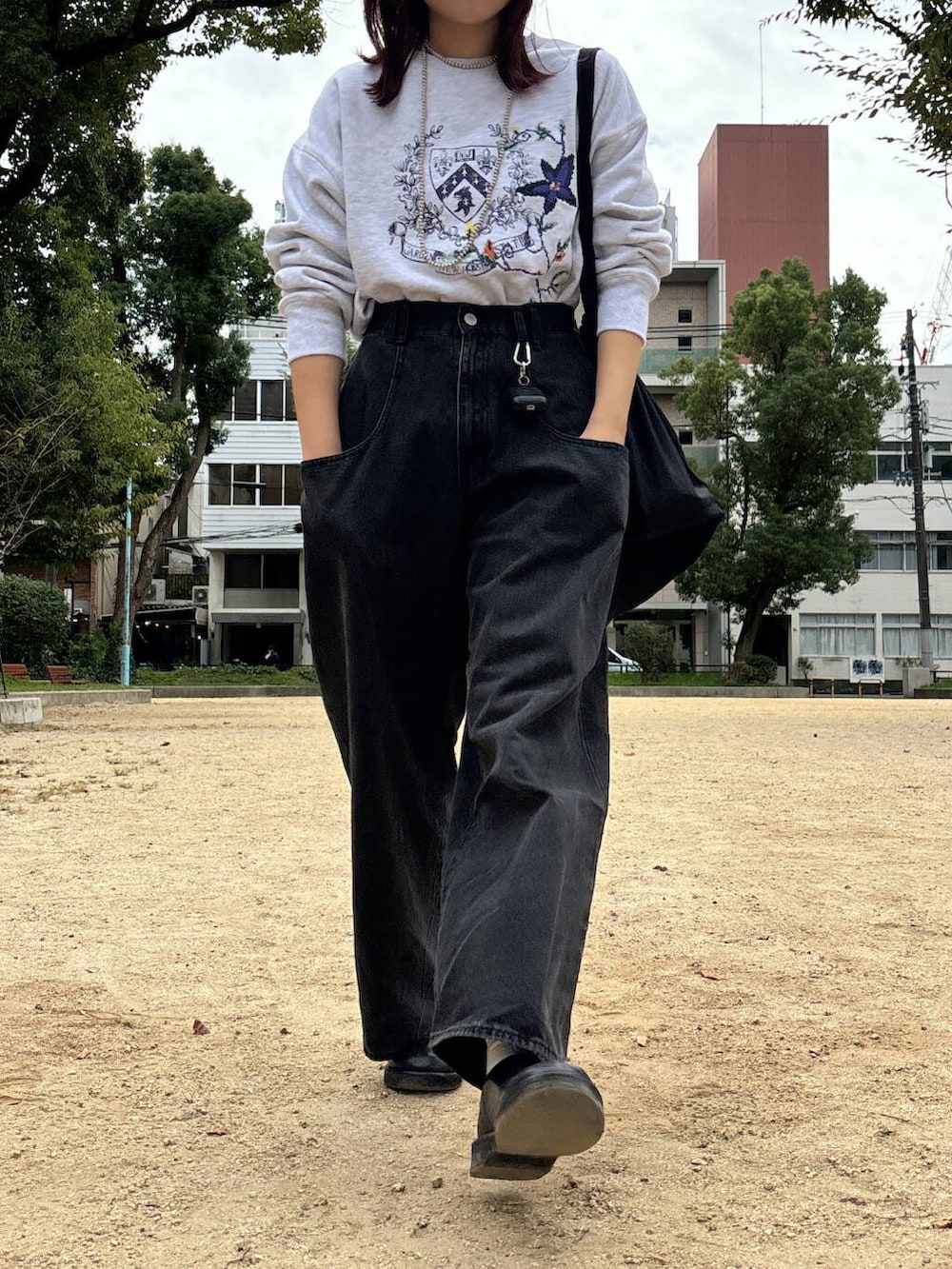 ブラック系のデニムパンツ、グレー系のスウェット、シルバー系のネックレスを着用したレディースの秋コーディネートの4枚目の写真