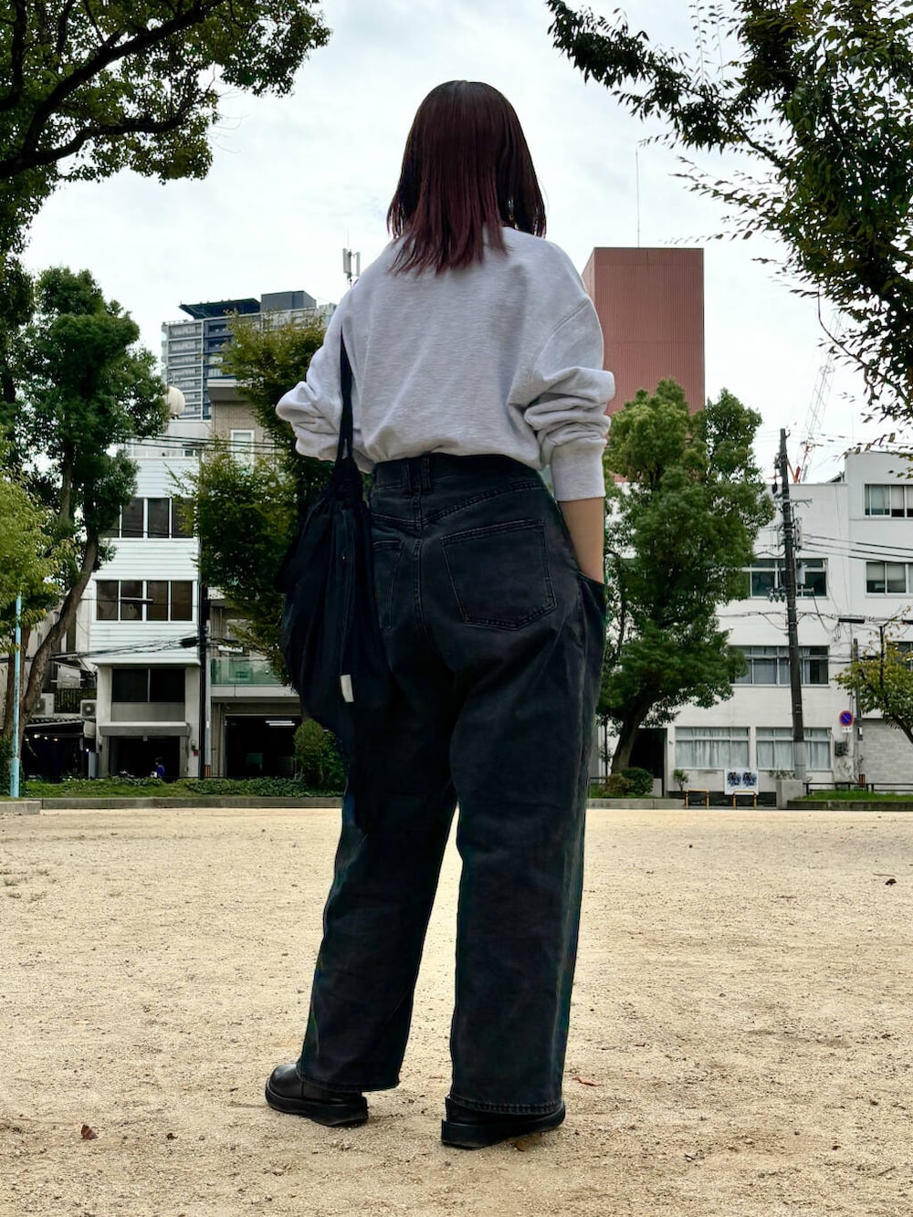 ブラック系のデニムパンツ、グレー系のスウェット、シルバー系のネックレスを着用したレディースの秋コーディネートの6枚目の写真