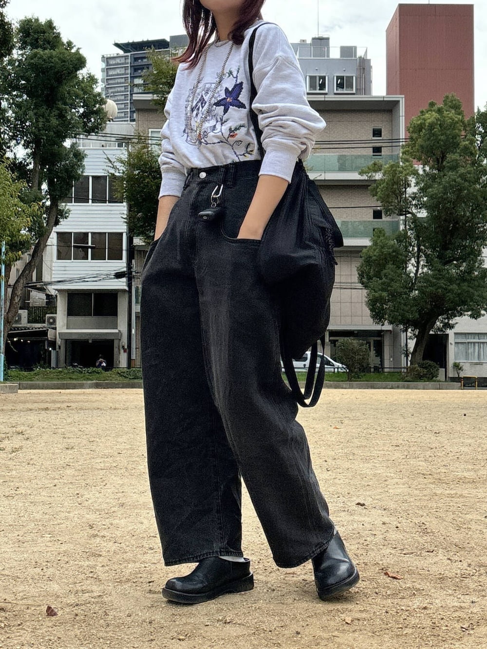 ブラック系のデニムパンツ、グレー系のスウェット、シルバー系のネックレスを着用したレディースの秋コーディネートの3枚目の写真