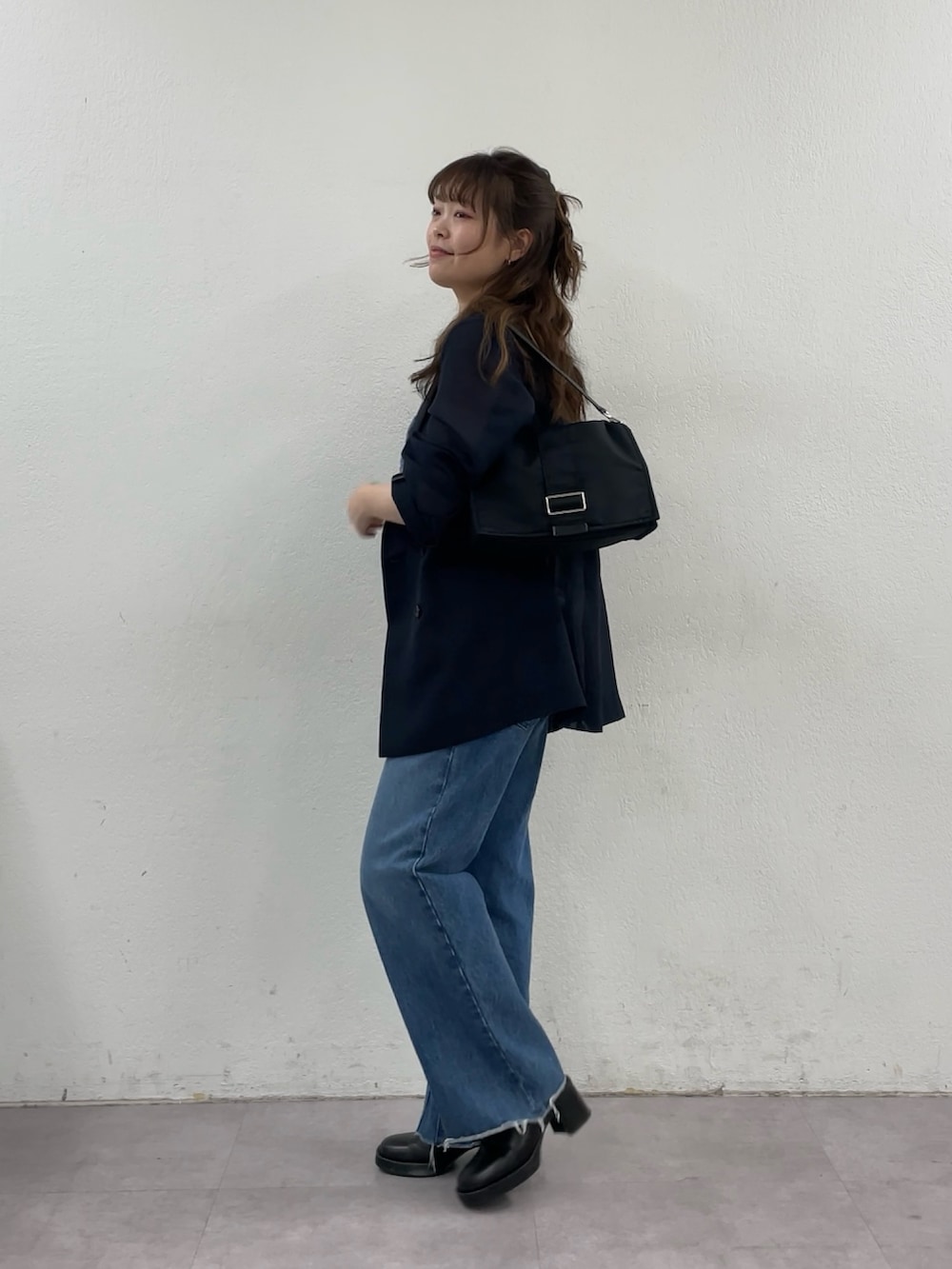 ブルー系のデニムパンツ、ブラック系のショルダーバッグ、ブルー系のテーラードジャケットを着用したレディースの春コーディネートの2枚目の写真