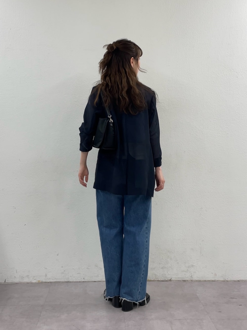 ブルー系のデニムパンツ、ブラック系のショルダーバッグ、ブルー系のテーラードジャケットを着用したレディースの春コーディネートの6枚目の写真