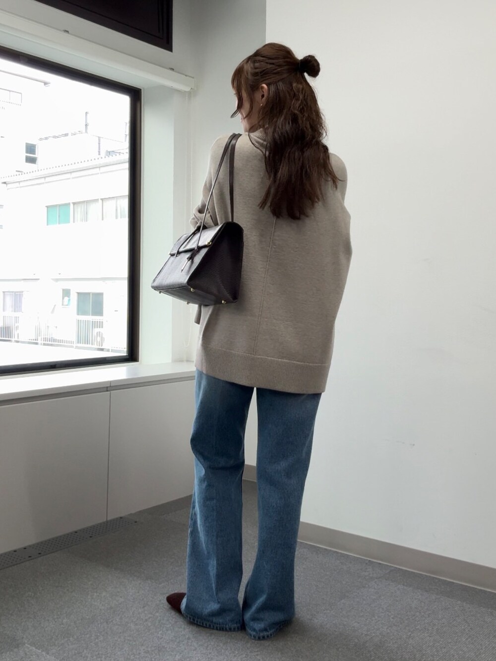 ブルー系のデニムパンツ、ベージュ系のニット/セーター、ブラウン系のトートバッグを着用したレディースの秋コーディネートの5枚目の写真