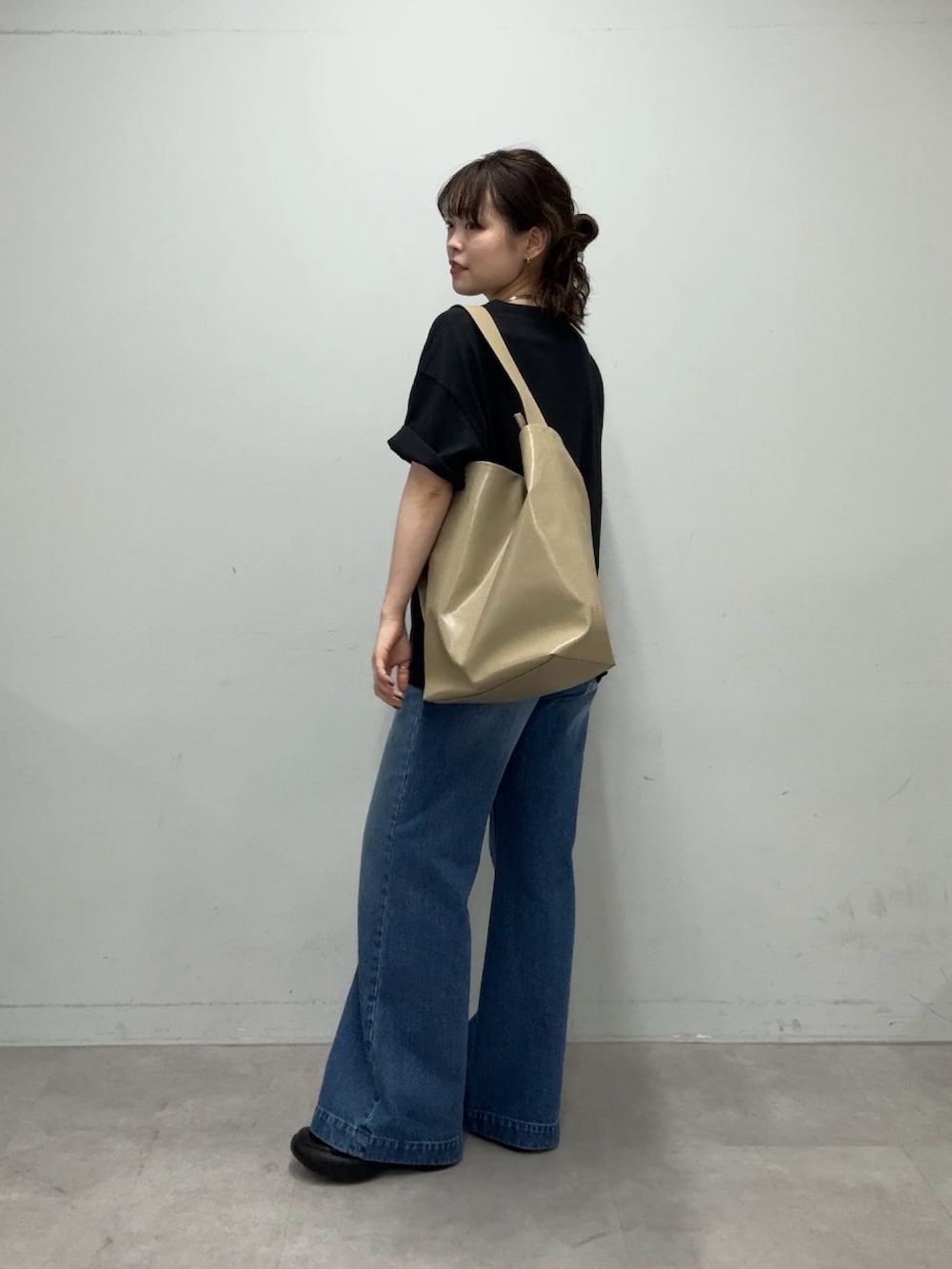 ブラック系のTシャツ/カットソー、ベージュ系のショルダーバッグ、ブルー系のデニムパンツを着用したレディースの春コーディネートの4枚目の写真