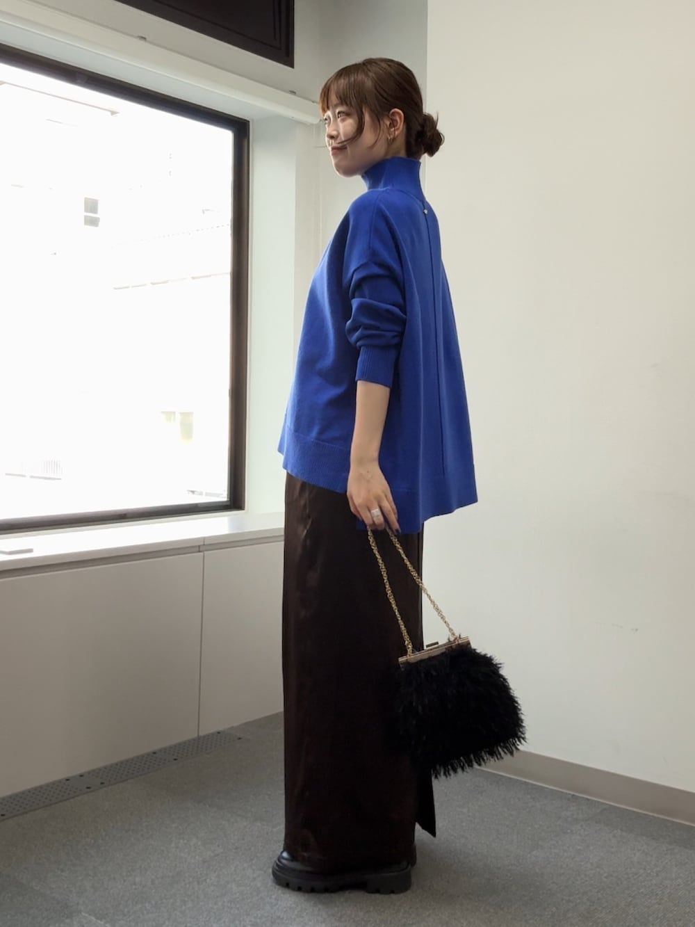 ブルー系のニット/セーター、ブラック系のショルダーバッグ、ブラウン系のスカートを着用したレディースの秋コーディネートの5枚目の写真
