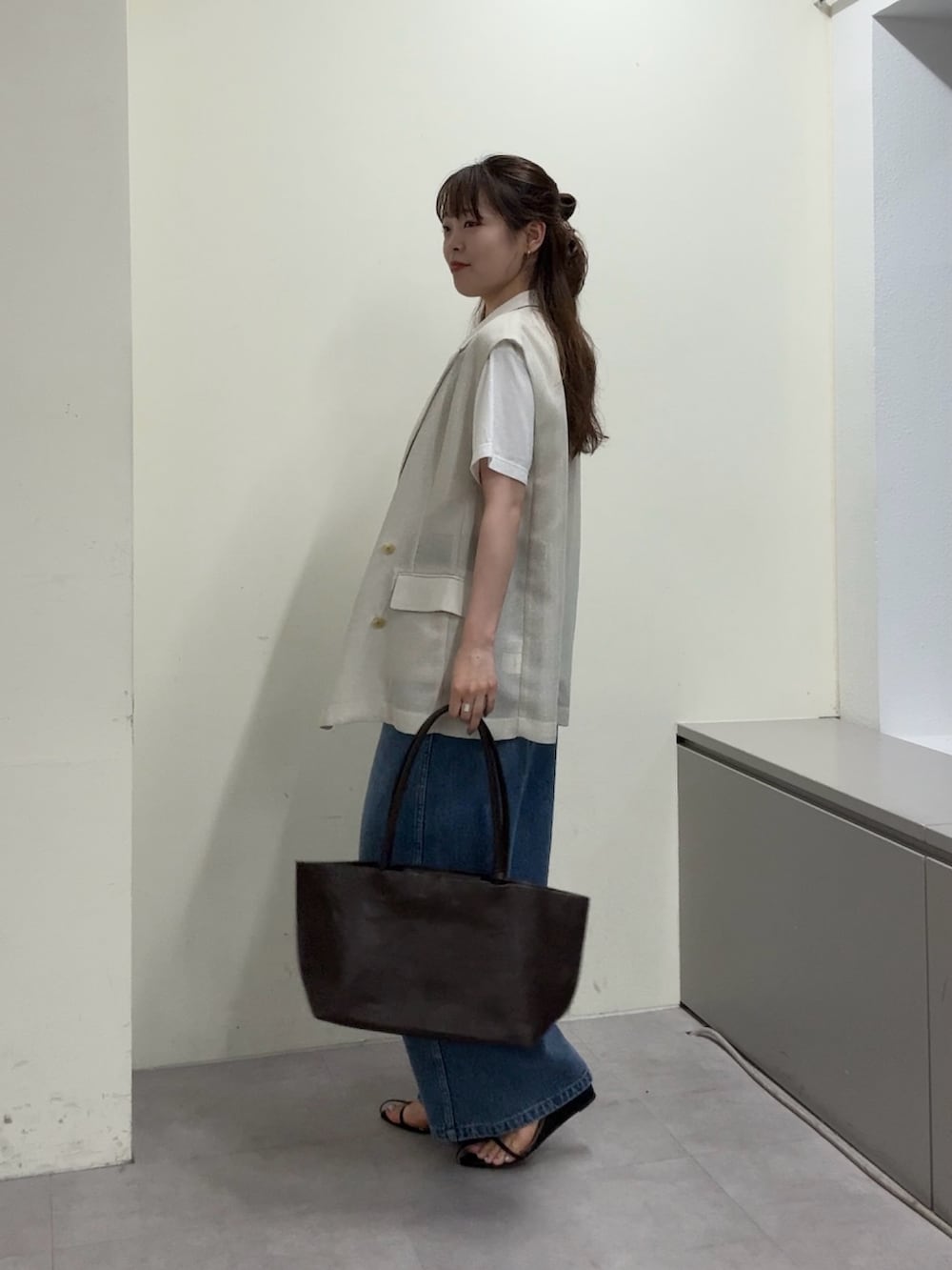ベージュ系のベスト、ホワイト系のTシャツ/カットソー、ブラック系のサンダルを着用したレディースの春コーディネートの2枚目の写真