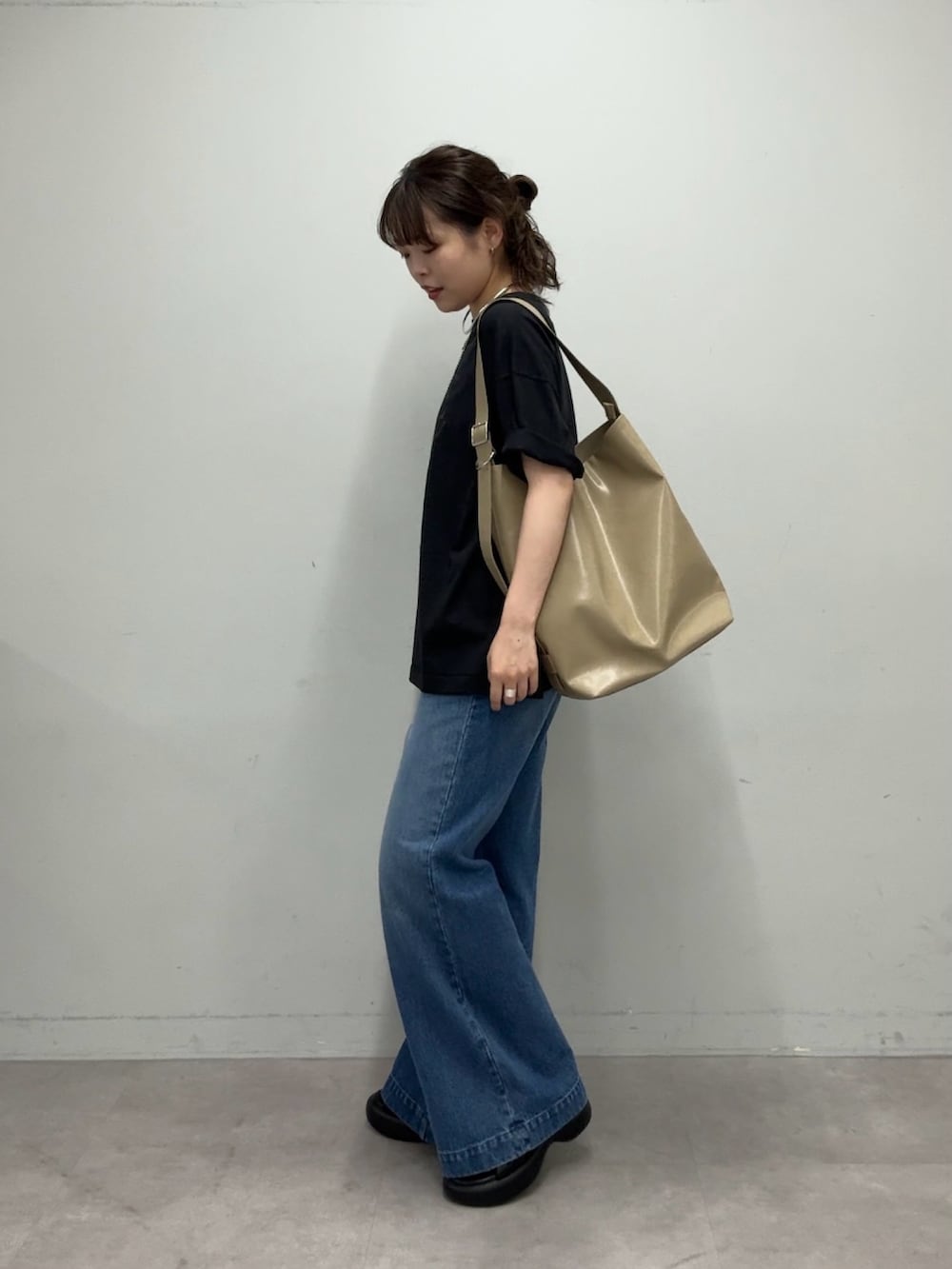 ブラック系のTシャツ/カットソー、ベージュ系のショルダーバッグ、ブルー系のデニムパンツを着用したレディースの春コーディネートの5枚目の写真