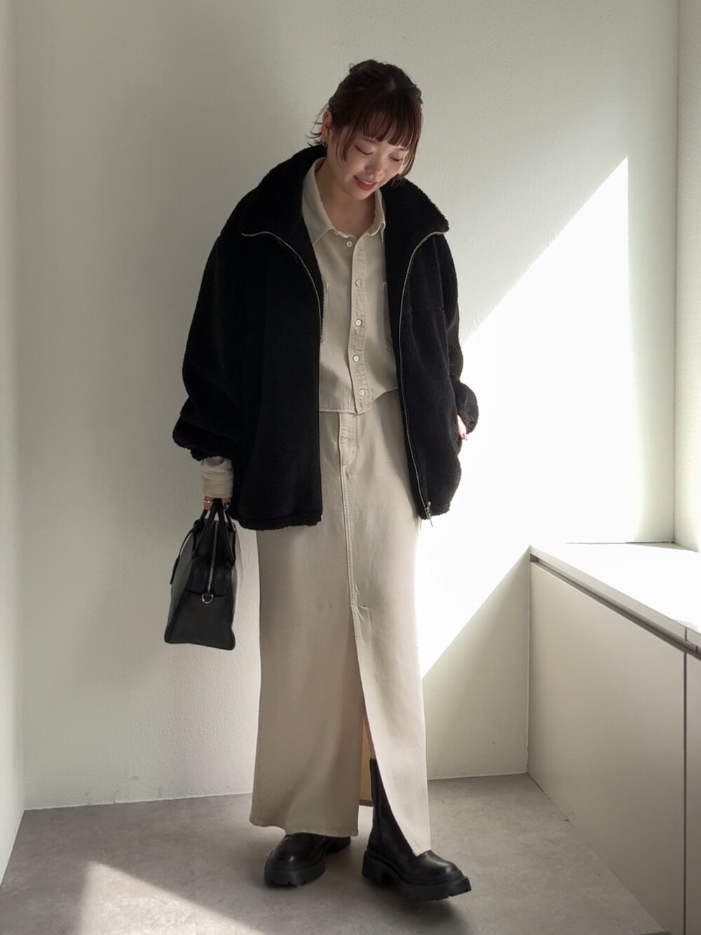 ブラック系のブーツ、ホワイト系のスカート、ブラック系のボストンバッグを着用したレディースの秋コーディネートの5枚目の写真