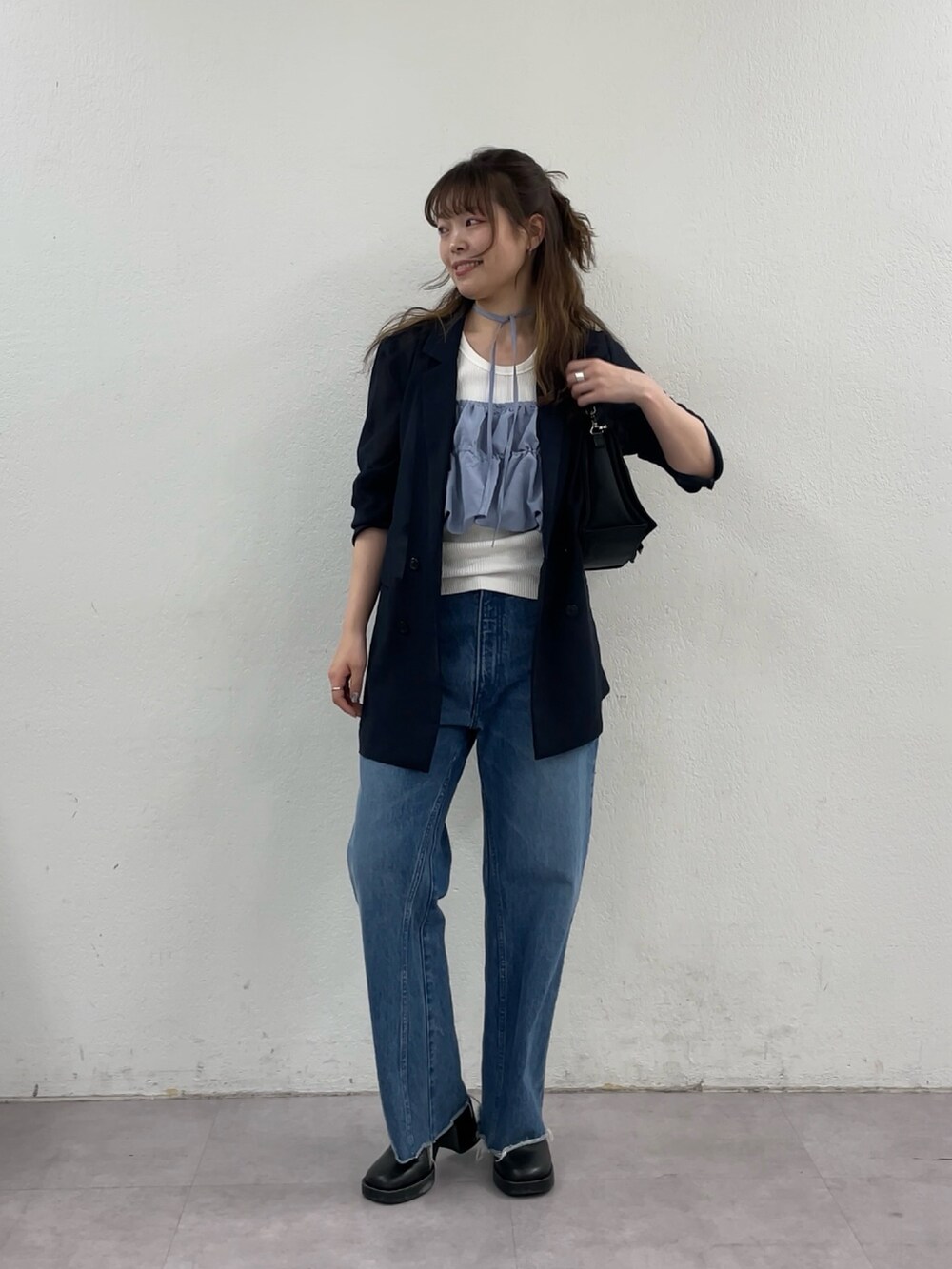 ブルー系のデニムパンツ、ブラック系のショルダーバッグ、ブルー系のテーラードジャケットを着用したレディースの春コーディネートの7枚目の写真