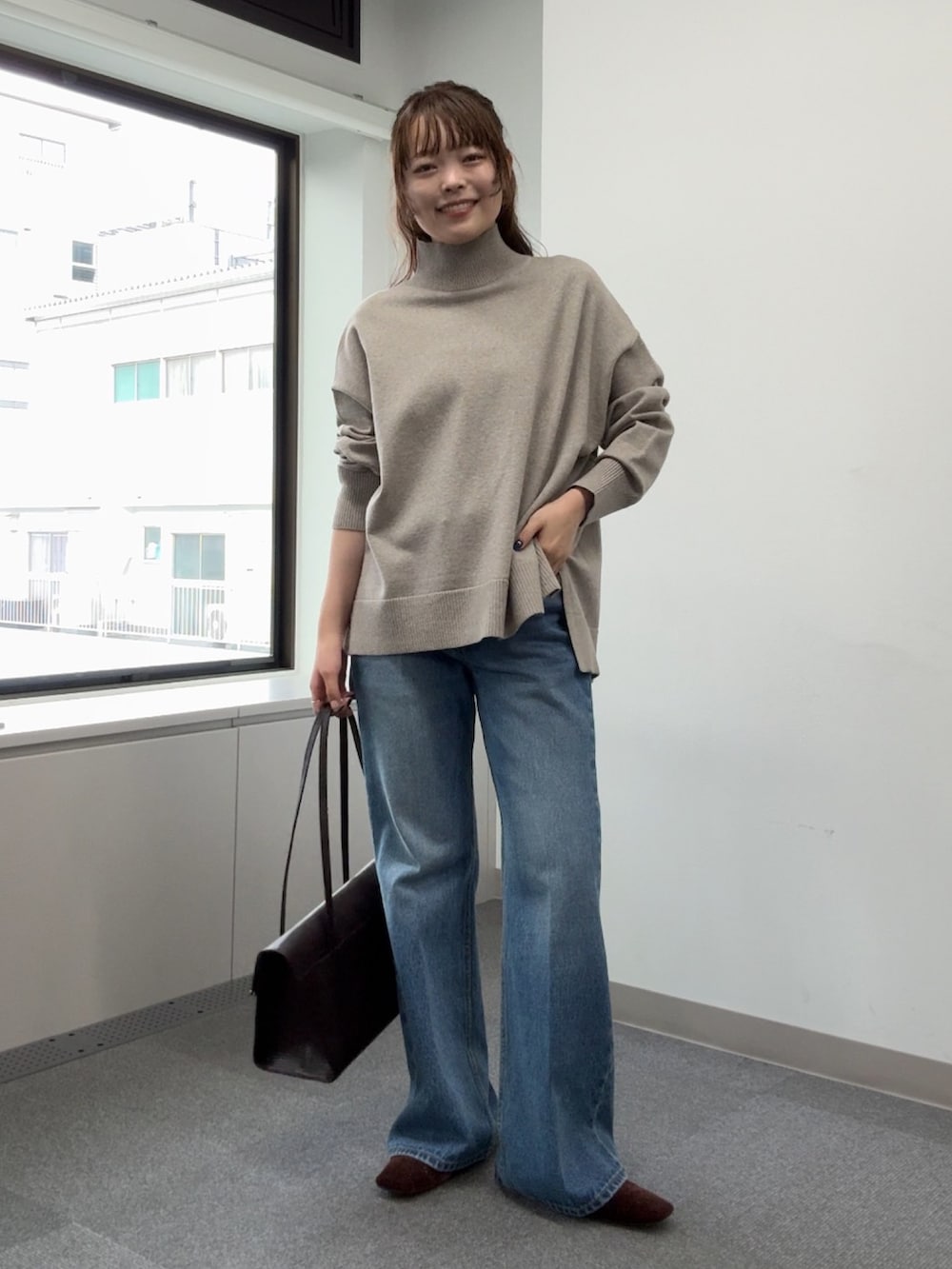 ブルー系のデニムパンツ、ベージュ系のニット/セーター、ブラウン系のトートバッグを着用したレディースの秋コーディネートの6枚目の写真