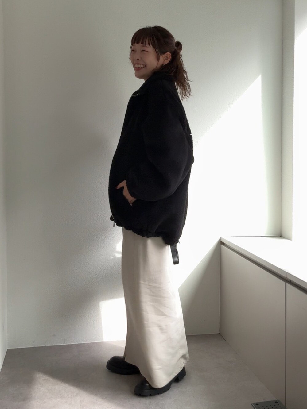 ブラック系のブーツ、ホワイト系のスカート、ブラック系のボストンバッグを着用したレディースの秋コーディネートの2枚目の写真