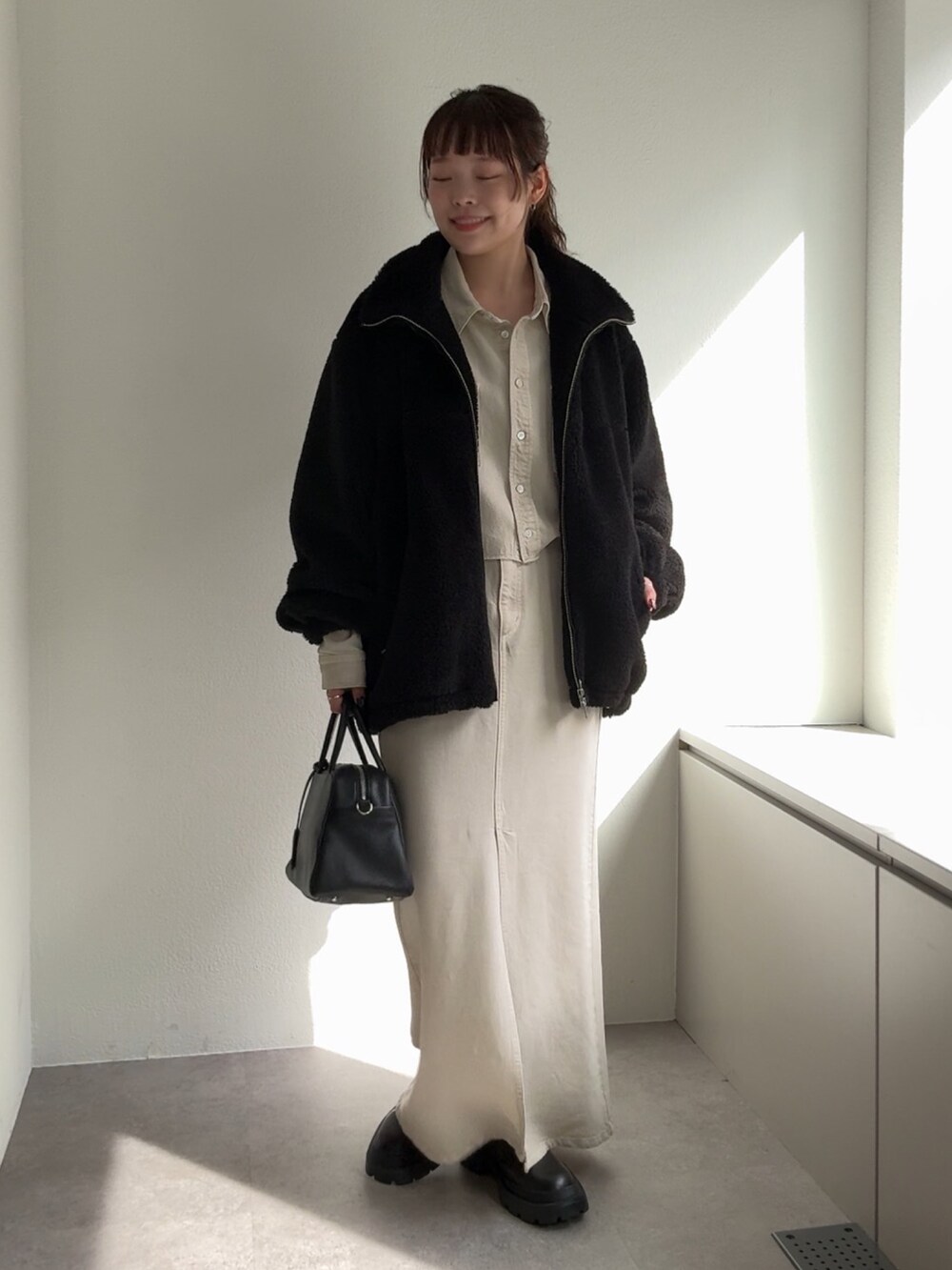 ブラック系のブーツ、ホワイト系のスカート、ブラック系のボストンバッグを着用したレディースの秋コーディネートの6枚目の写真