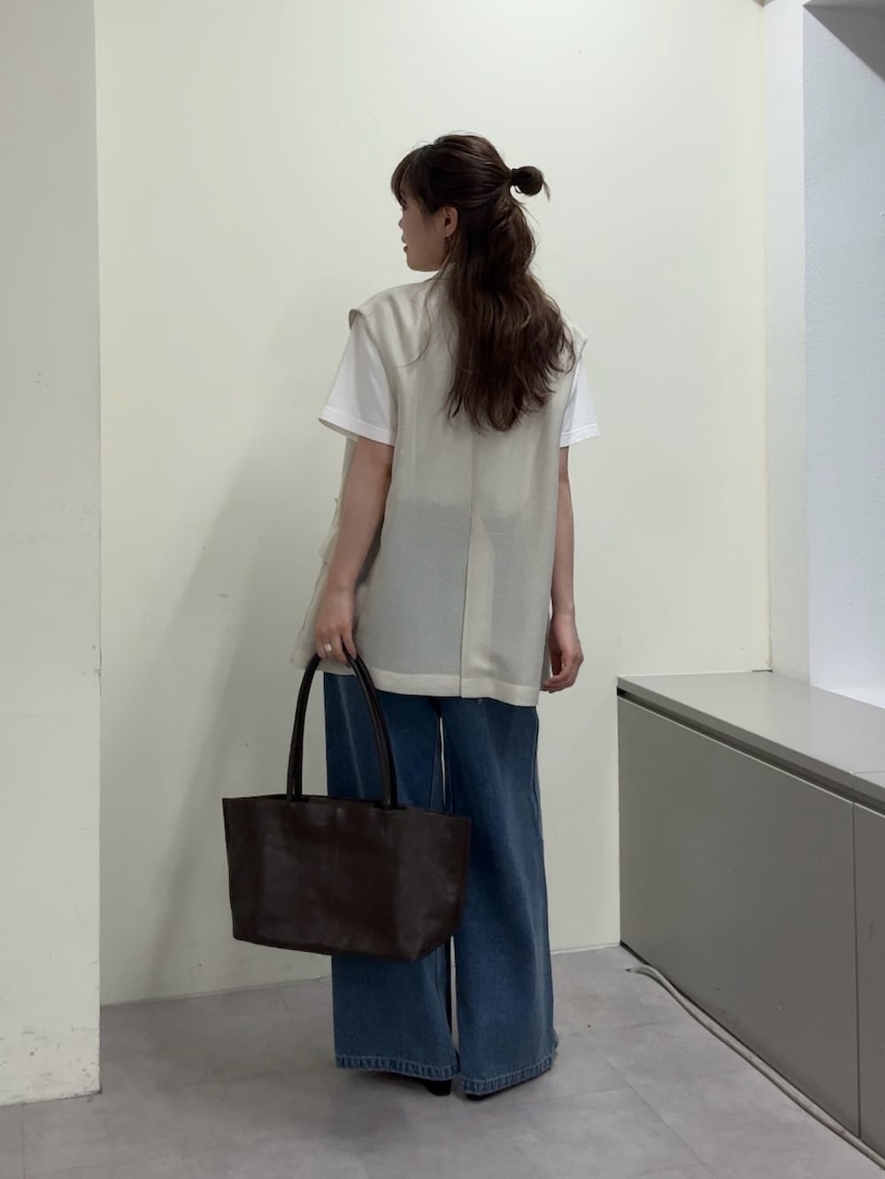 ベージュ系のベスト、ホワイト系のTシャツ/カットソー、ブラック系のサンダルを着用したレディースの春コーディネートの3枚目の写真