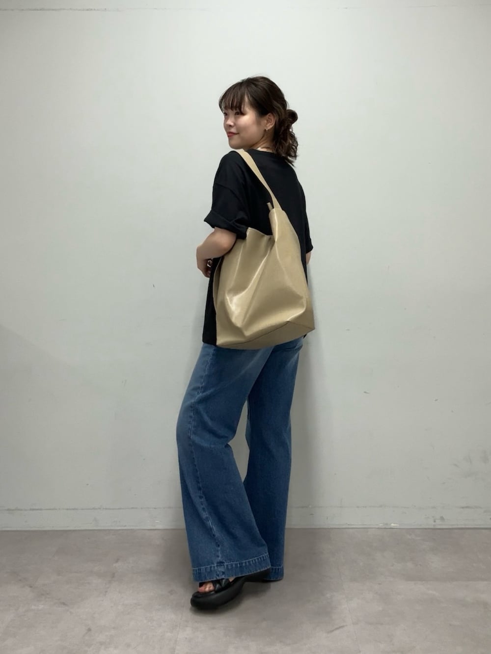 ブラック系のTシャツ/カットソー、ベージュ系のショルダーバッグ、ブルー系のデニムパンツを着用したレディースの春コーディネートの2枚目の写真