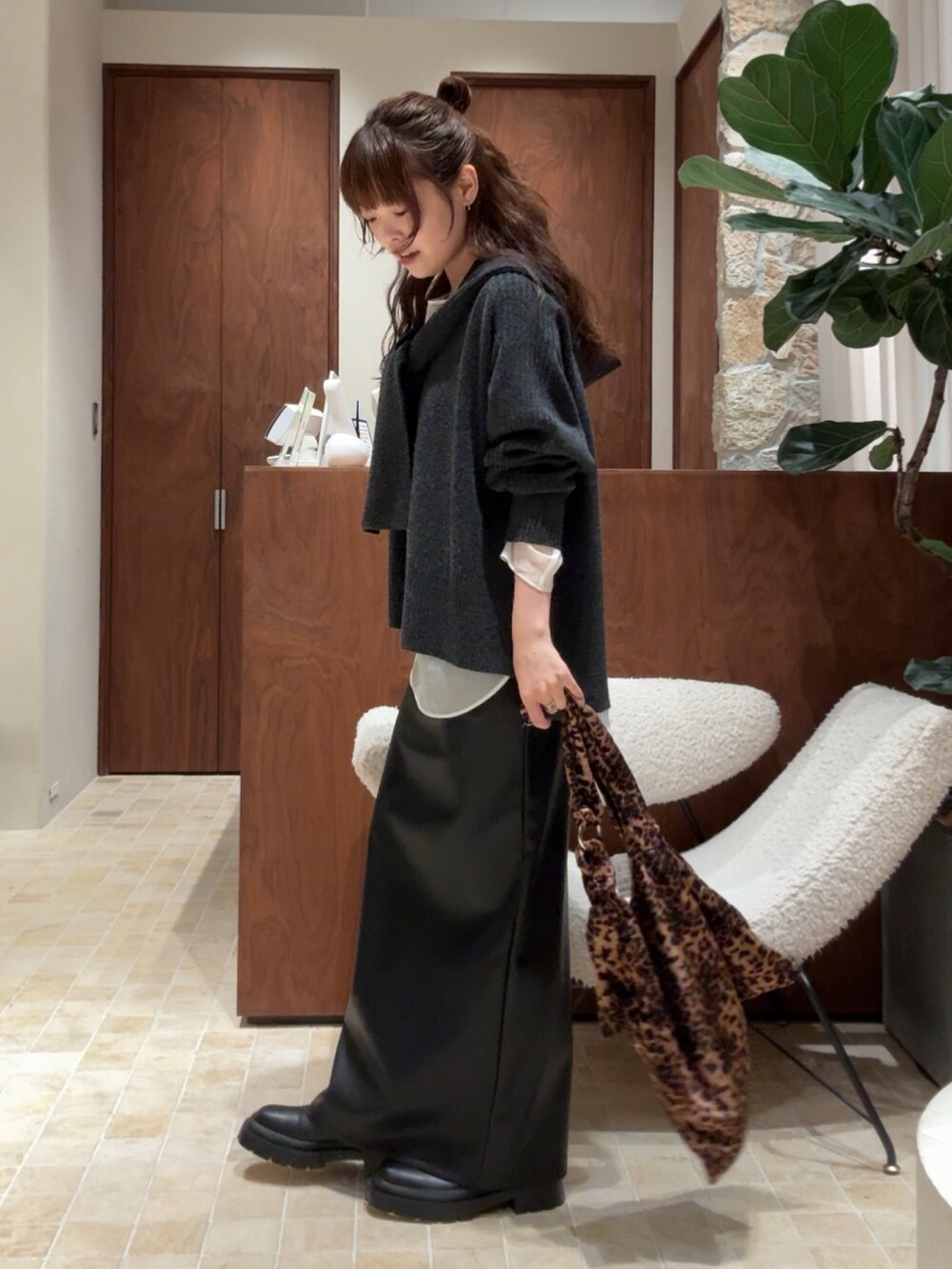 グレー系のニット/セーター、ブラック系のスカート、ブラック系のブーツを着用したレディースの秋コーディネートの5枚目の写真