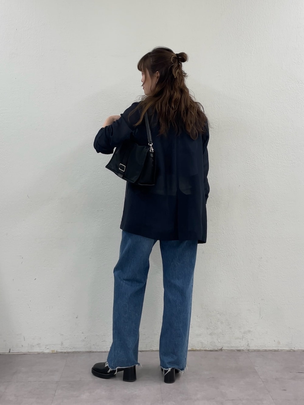 ブルー系のデニムパンツ、ブラック系のショルダーバッグ、ブルー系のテーラードジャケットを着用したレディースの春コーディネートの3枚目の写真