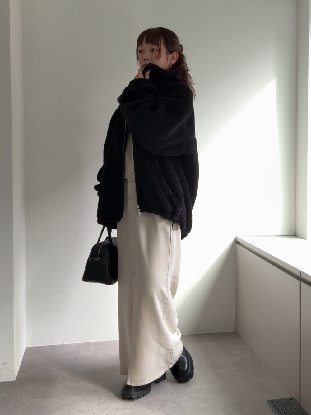 ブラック系のブーツ、ホワイト系のスカート、ブラック系のボストンバッグを着用したレディースの秋コーディネートの4枚目の写真