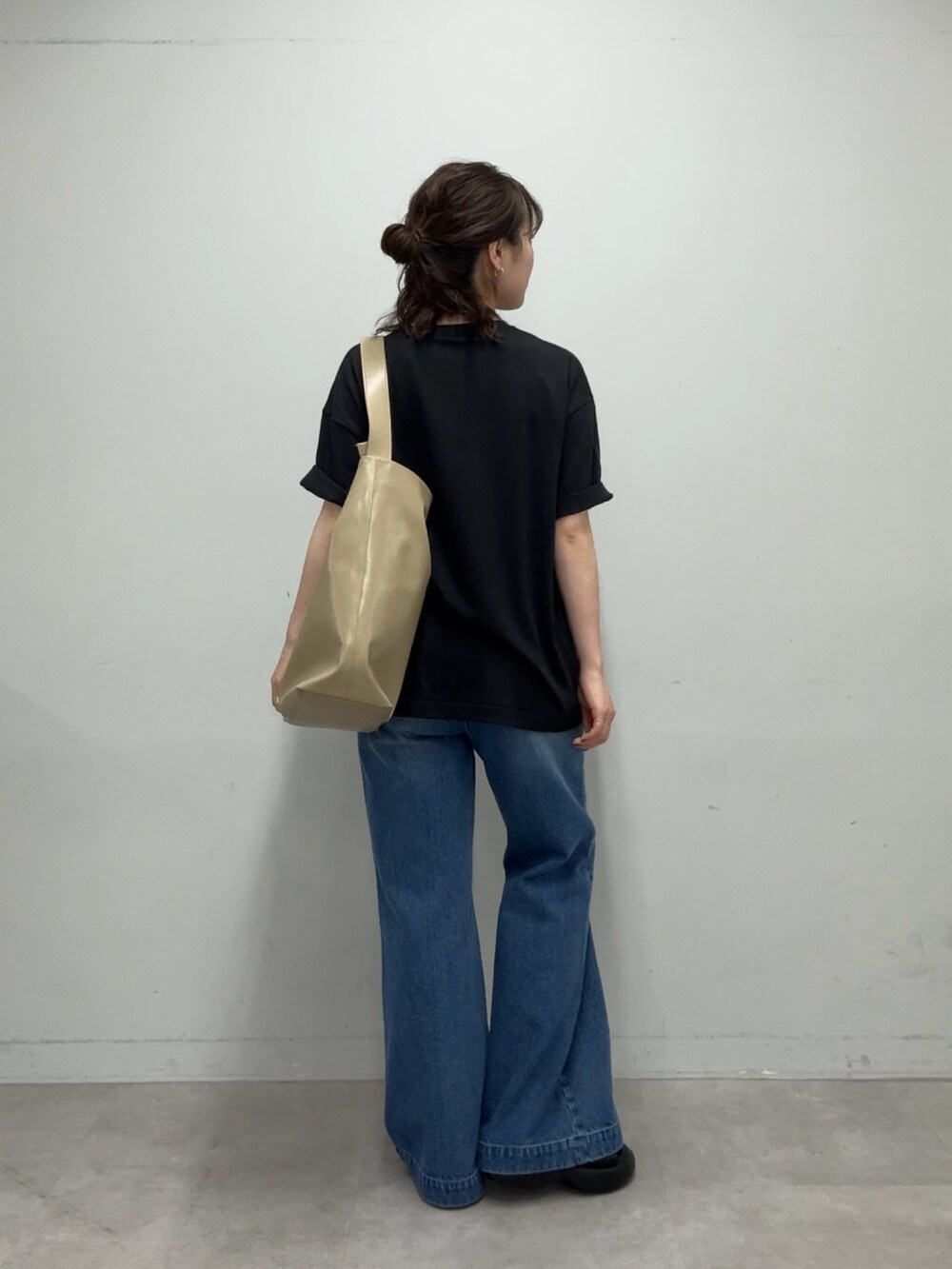 ブラック系のTシャツ/カットソー、ベージュ系のショルダーバッグ、ブルー系のデニムパンツを着用したレディースの春コーディネートの6枚目の写真