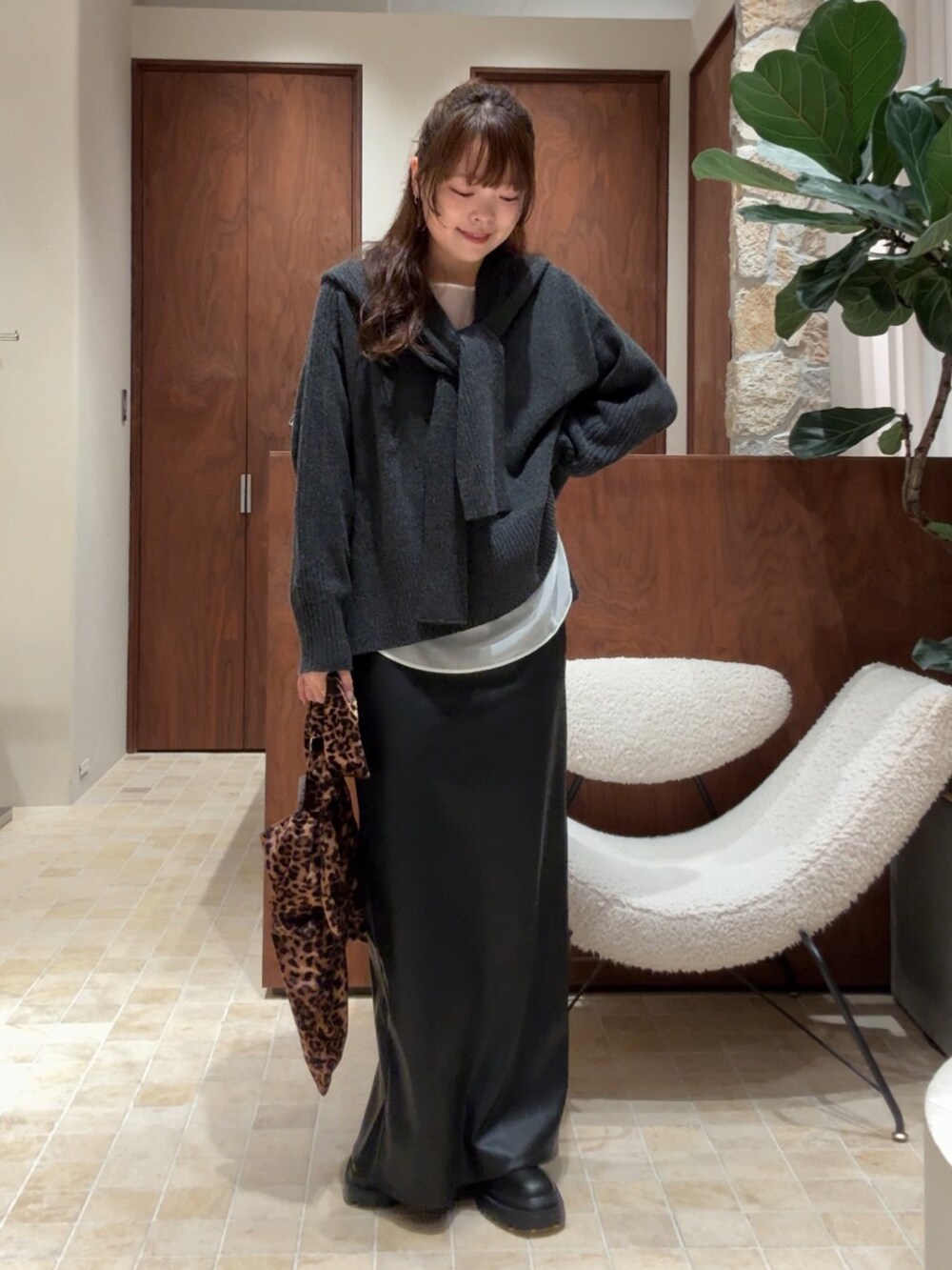 グレー系のニット/セーター、ブラック系のスカート、ブラック系のブーツを着用したレディースの秋コーディネートの4枚目の写真