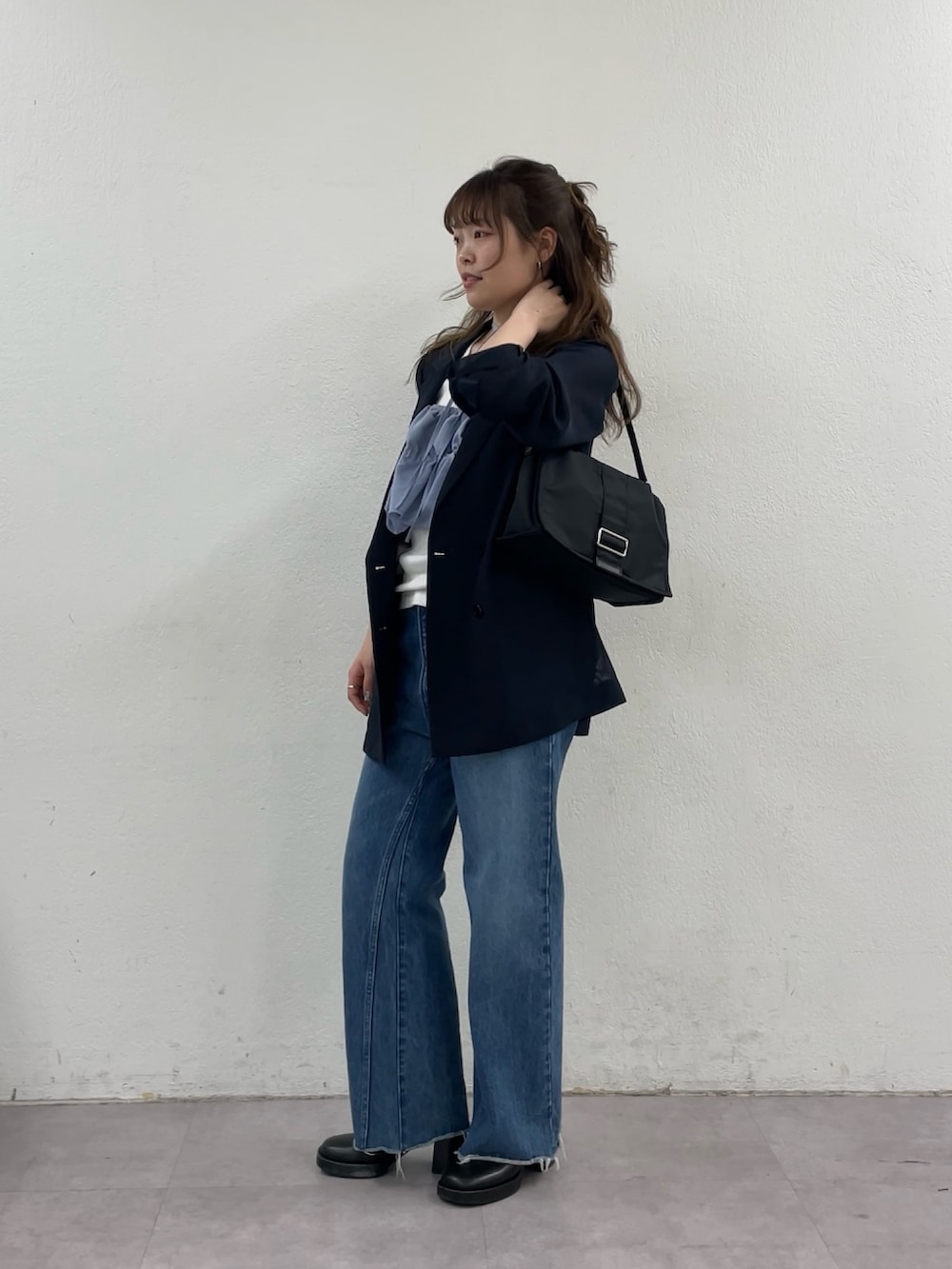 ブルー系のデニムパンツ、ブラック系のショルダーバッグ、ブルー系のテーラードジャケットを着用したレディースの春コーディネートの5枚目の写真