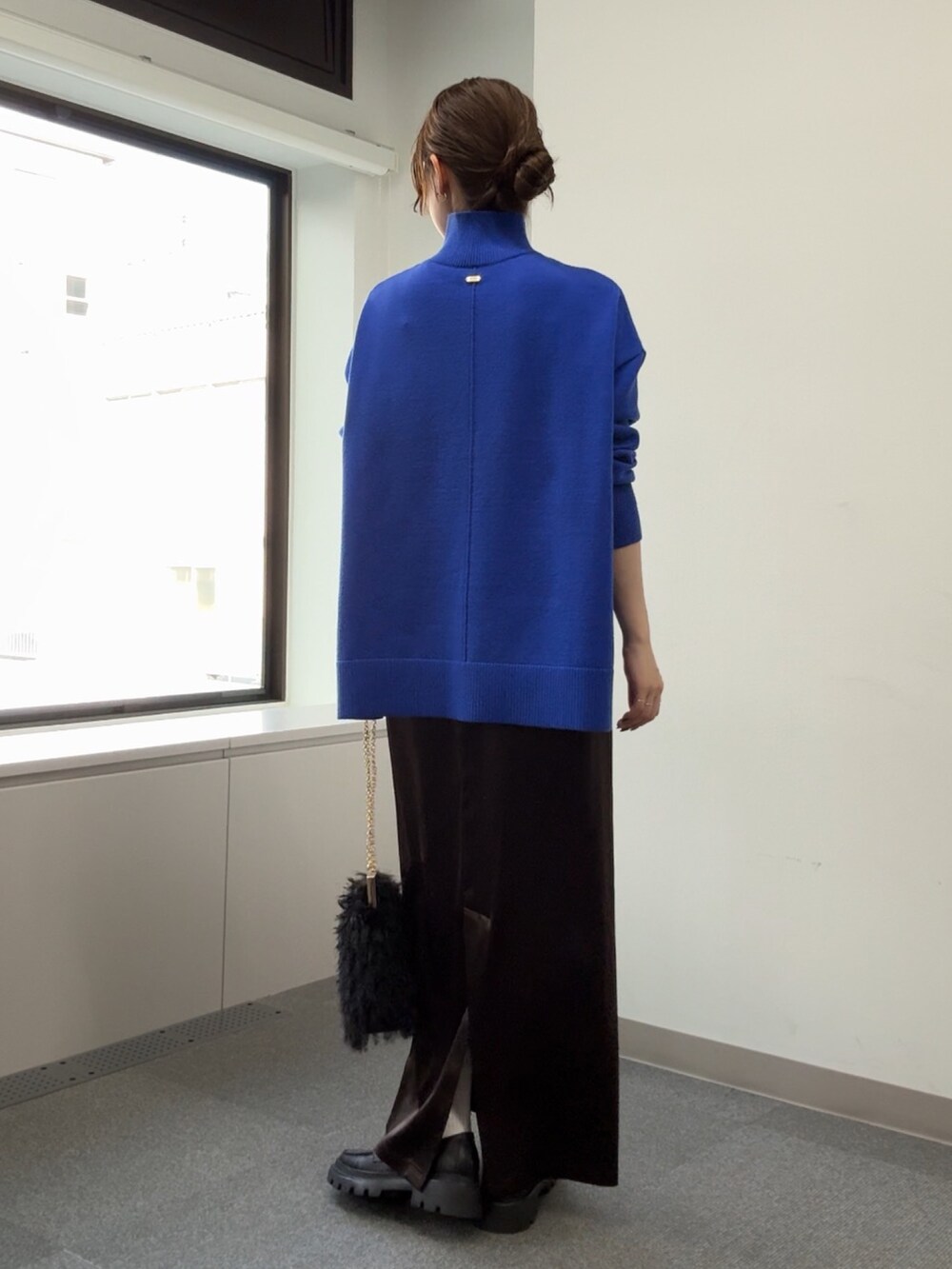 ブルー系のニット/セーター、ブラック系のショルダーバッグ、ブラウン系のスカートを着用したレディースの秋コーディネートの7枚目の写真