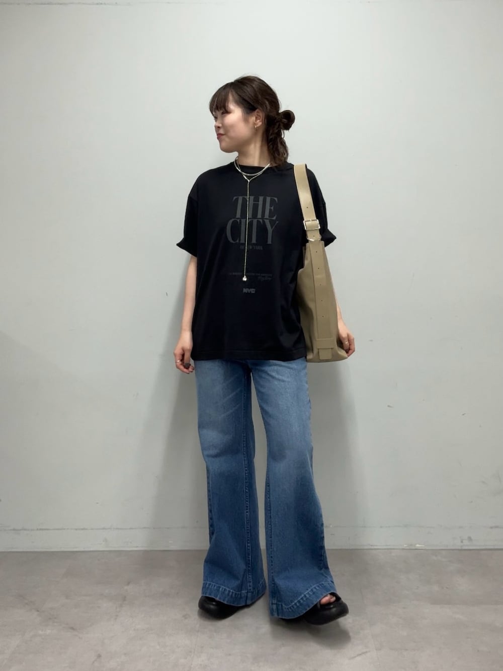 ブラック系のTシャツ/カットソー、ベージュ系のショルダーバッグ、ブルー系のデニムパンツを着用したレディースの春コーディネートの3枚目の写真