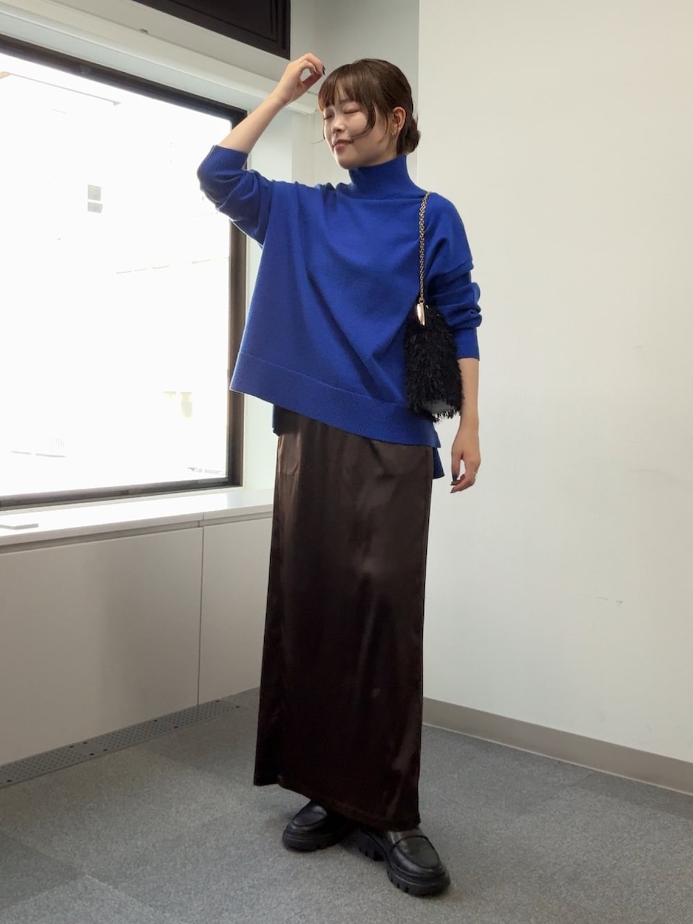 ブルー系のニット/セーター、ブラック系のショルダーバッグ、ブラウン系のスカートを着用したレディースの秋コーディネートの4枚目の写真