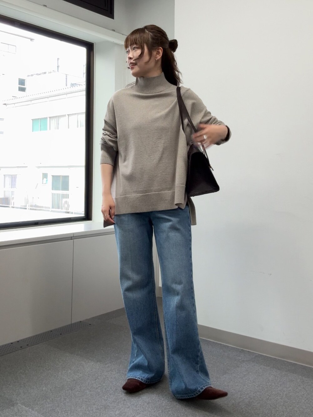 ブルー系のデニムパンツ、ベージュ系のニット/セーター、ブラウン系のトートバッグを着用したレディースの秋コーディネートの3枚目の写真