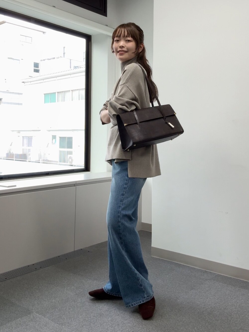 ブルー系のデニムパンツ、ベージュ系のニット/セーター、ブラウン系のトートバッグを着用したレディースの秋コーディネートの4枚目の写真