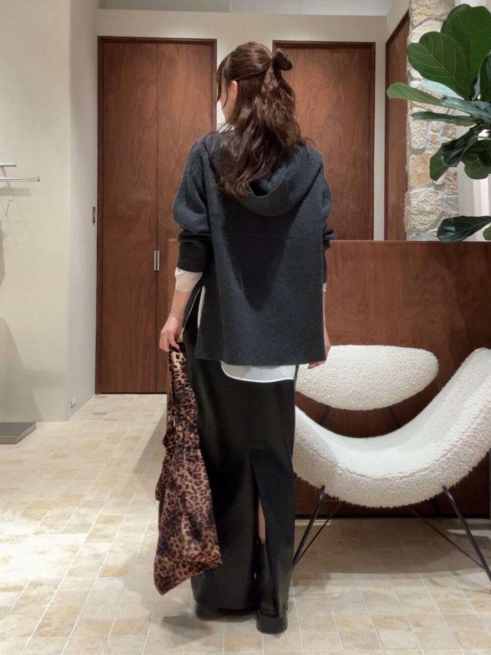 グレー系のニット/セーター、ブラック系のスカート、ブラック系のブーツを着用したレディースの秋コーディネートの3枚目の写真