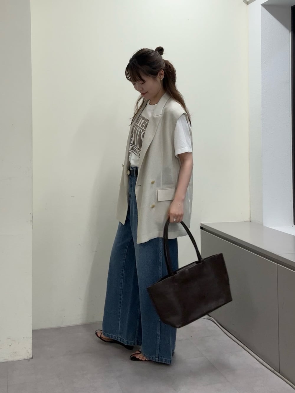 ベージュ系のベスト、ホワイト系のTシャツ/カットソー、ブラック系のサンダルを着用したレディースの春コーディネートの5枚目の写真