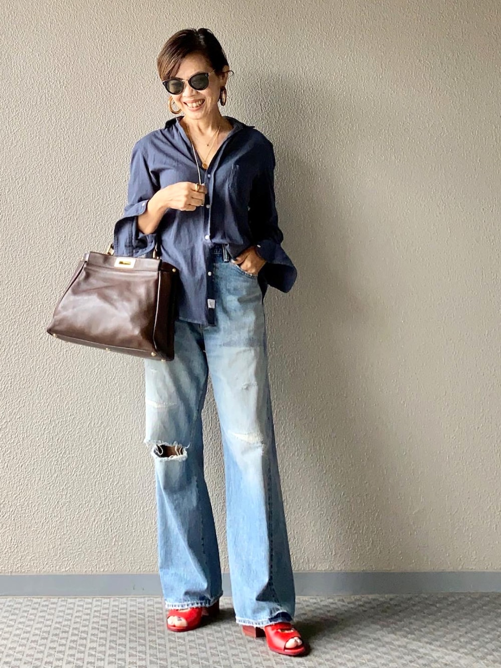 ブルー系のデニムパンツ、ブルー系のシャツ/ブラウス、ブラウン系のバッグを着用したレディースの夏コーディネートの2枚目の写真