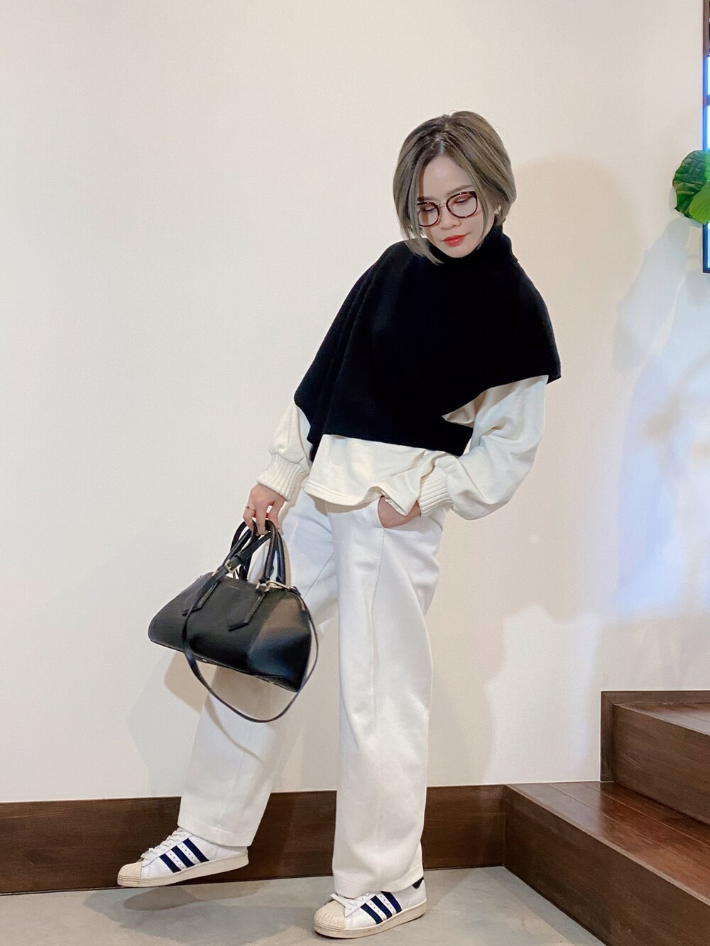 ブラック系のニット/セーター、ホワイト系のその他パンツ、ブルー系のスニーカーを着用したレディースの冬コーディネートの2枚目の写真