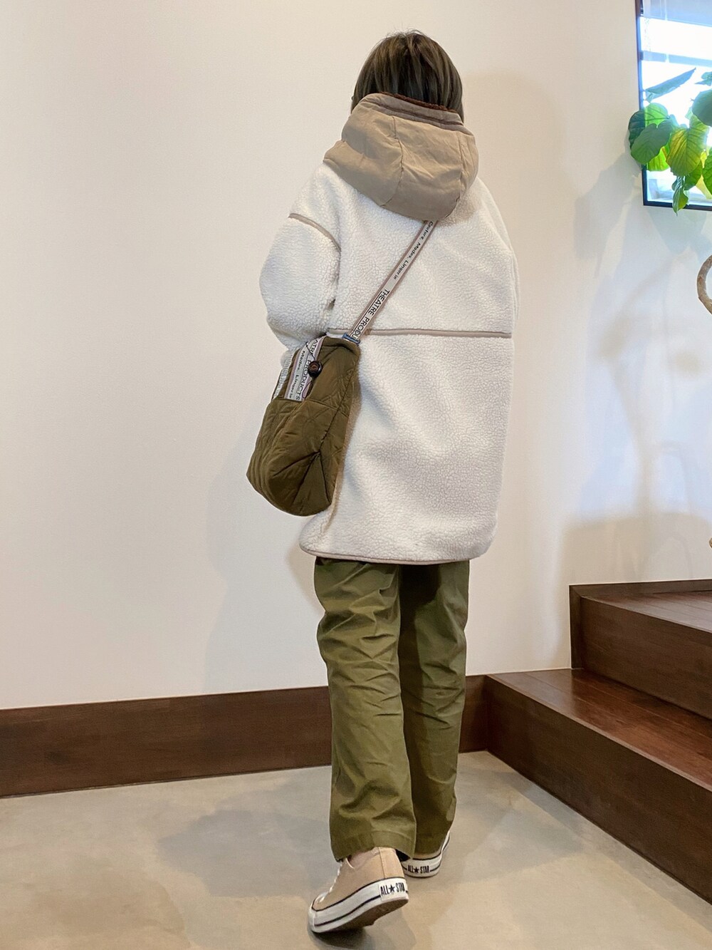 ホワイト系のムートンコート、グリーン系のトートバッグ、ベージュ系のスニーカーを着用したレディースの冬コーディネートの2枚目の写真