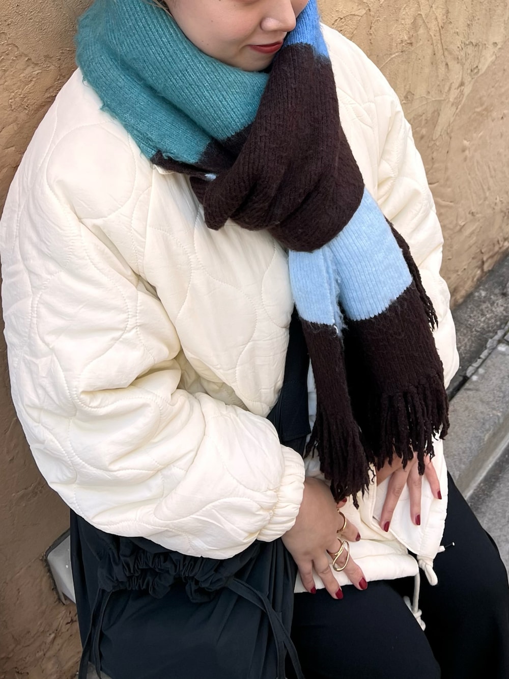 ホワイト系のダウンジャケット/コート、グレー系のスニーカー、ブルー系のマフラーを着用したレディースの冬コーディネートの2枚目の写真