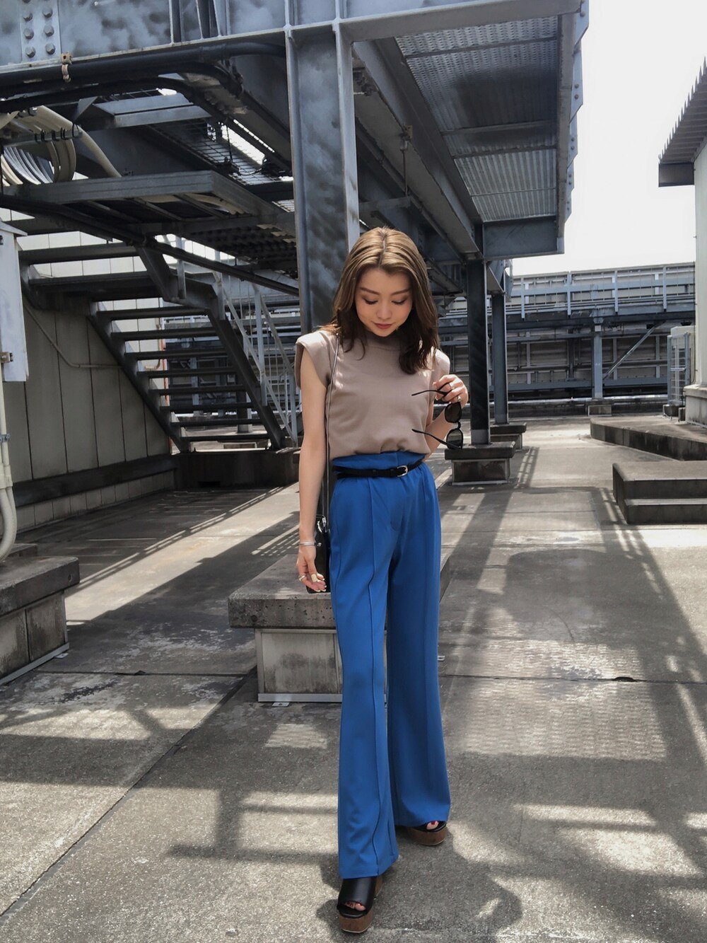 ベージュ系のタンクトップ、ブルー系のスラックス、ブラック系のサンダルを着用したレディースの夏コーディネートの2枚目の写真