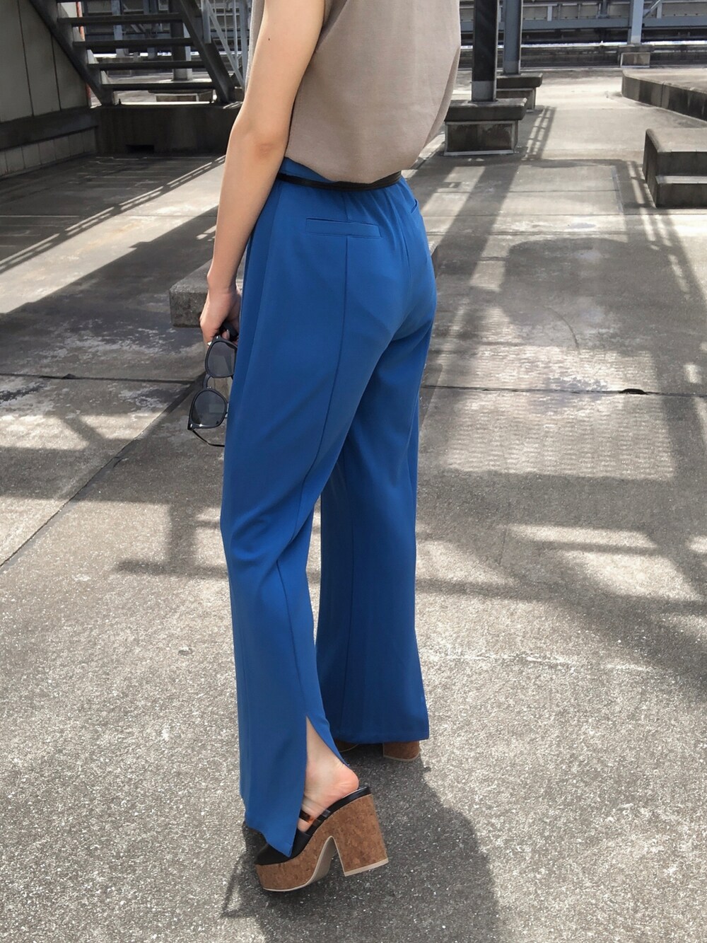 ベージュ系のタンクトップ、ブルー系のスラックス、ブラック系のサンダルを着用したレディースの夏コーディネートの4枚目の写真