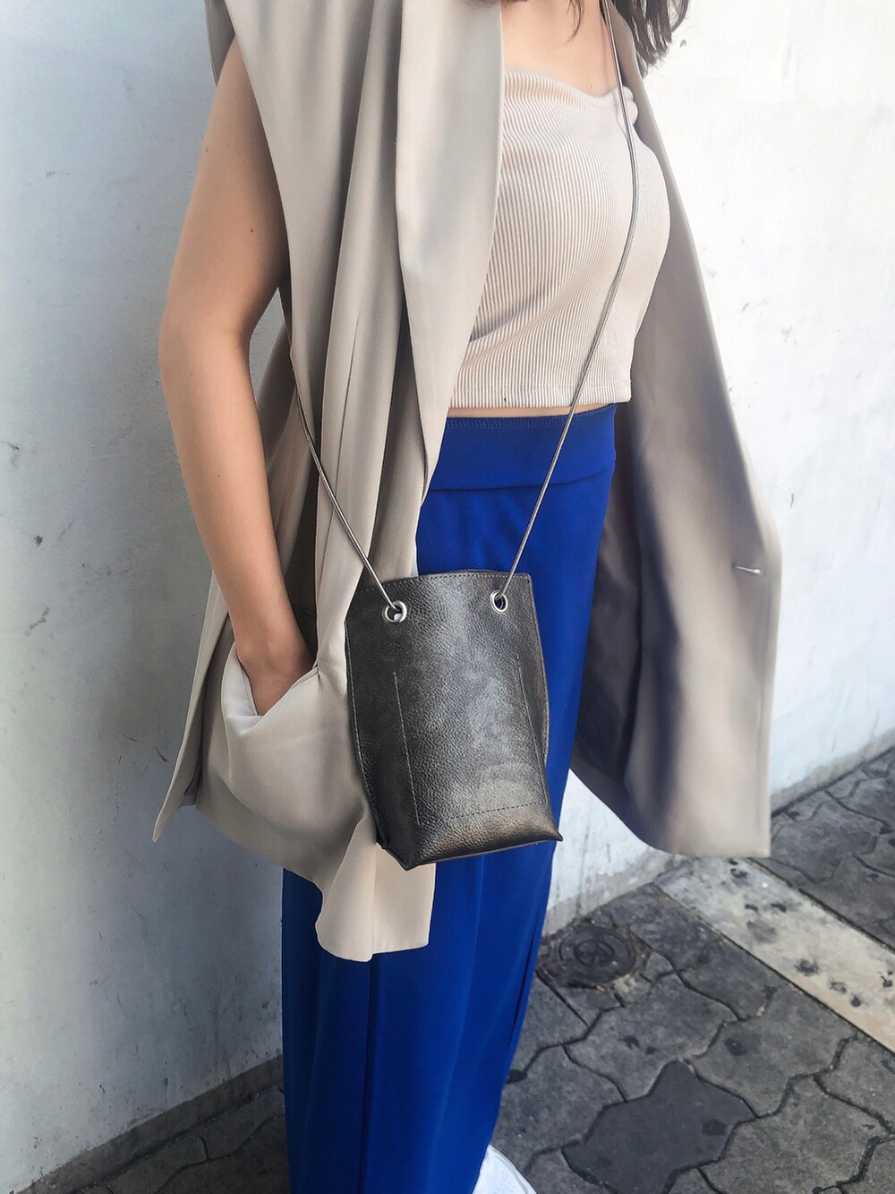 ブルー系のスカート、ホワイト系のキャミソール、ベージュ系のベストを着用したレディースの夏コーディネートの4枚目の写真