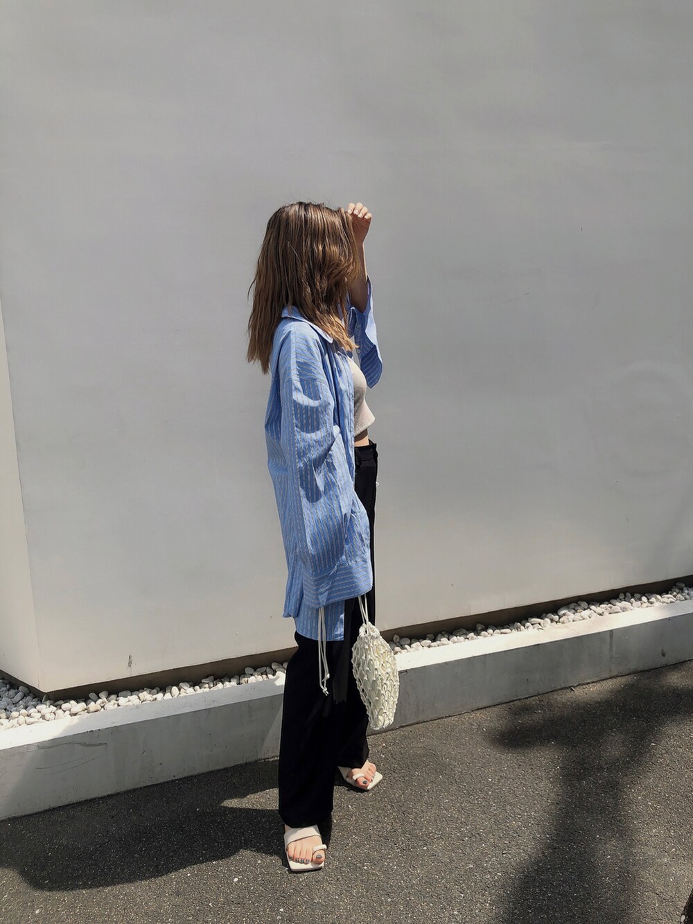 ブルー系のシャツ/ブラウス、ホワイト系のハンドバッグ、ホワイト系のサンダルを着用したレディースの夏コーディネートの2枚目の写真